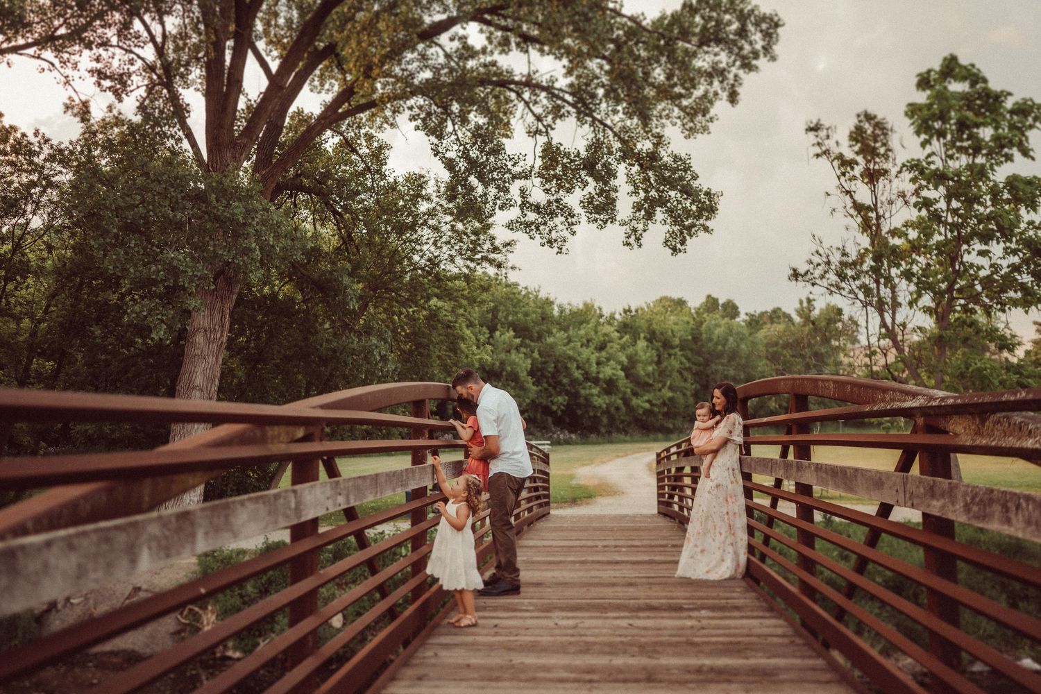 A romantic sunset moment captured on a wooden bridge surrounded by lush trees and nature.