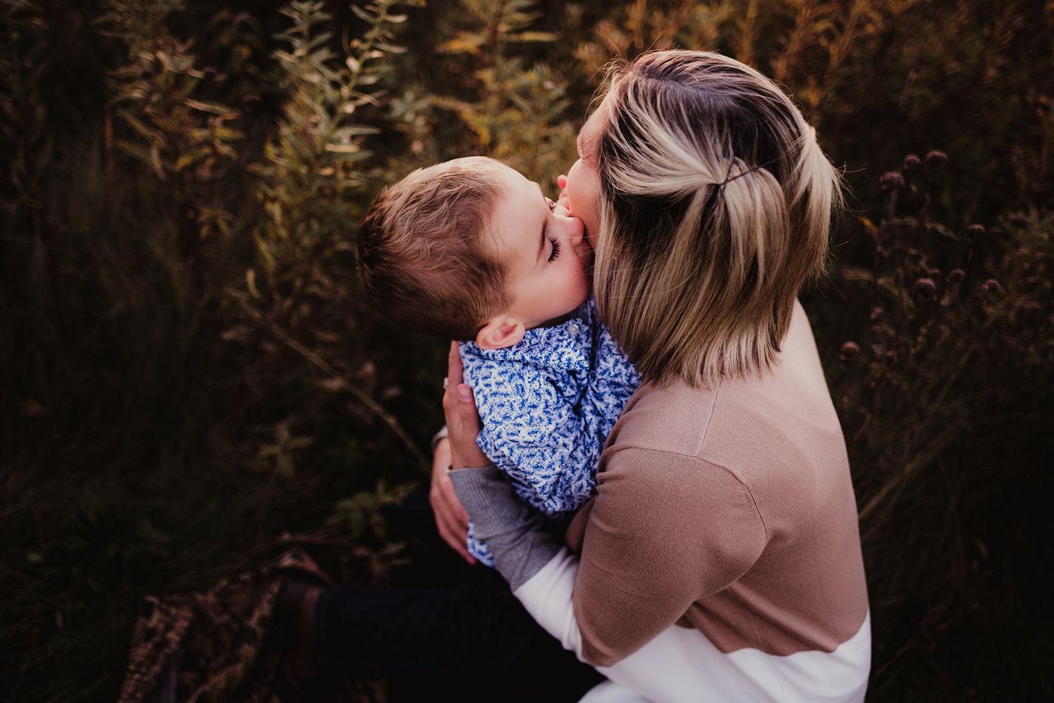 Tender embrace between adult and young child during golden hour photoshoot in nature.