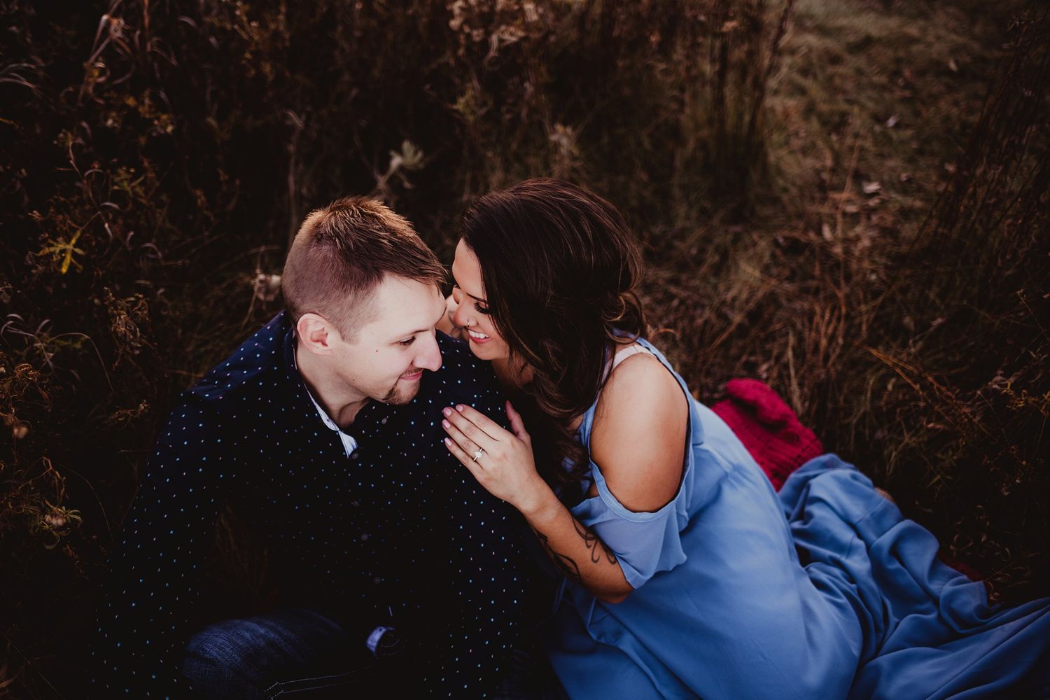 Intimate couple sharing a tender moment in casual clothing against a dark outdoor backdrop.