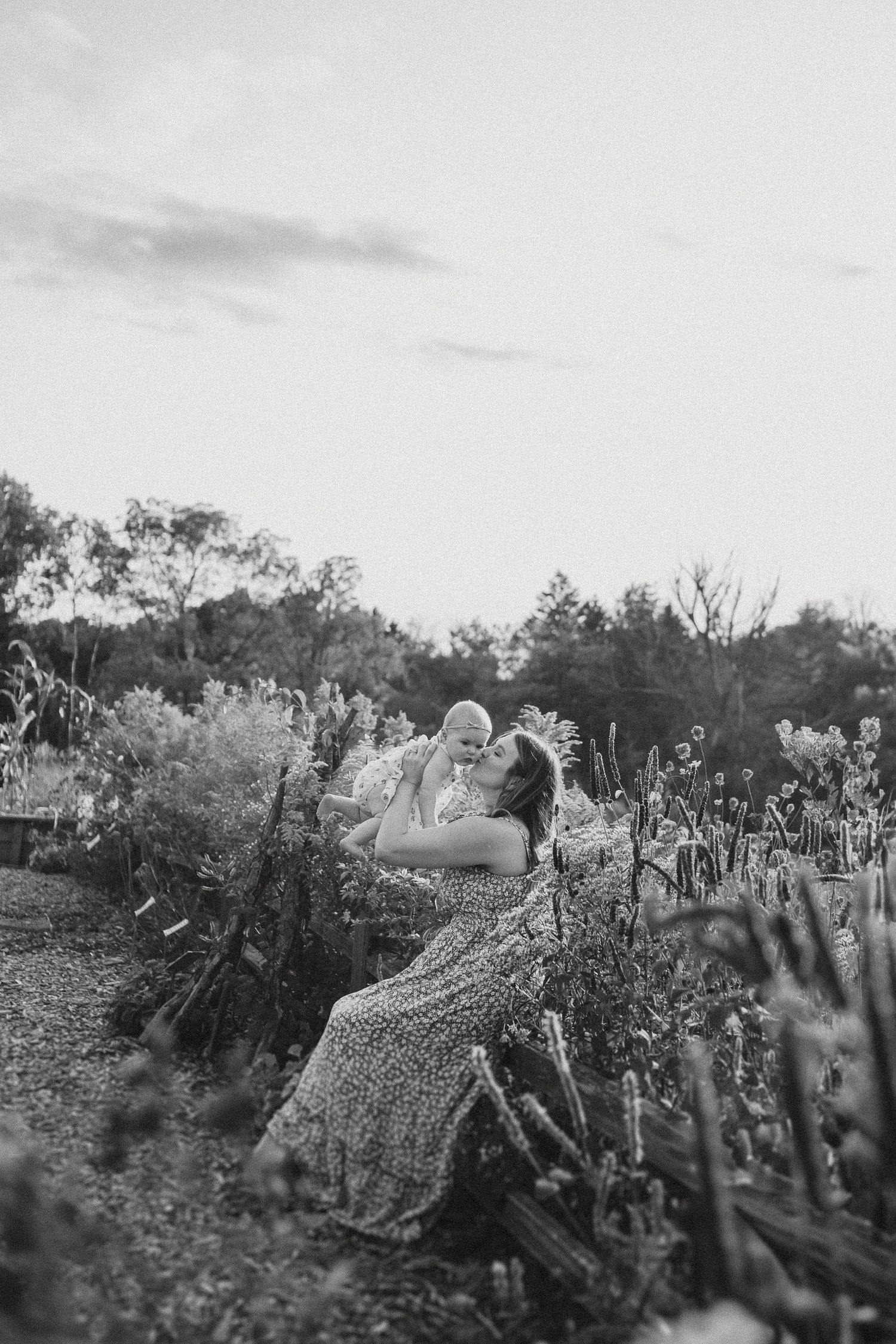 A couple sits intimately in a garden filled with wildflowers at sunset captured in black and white.