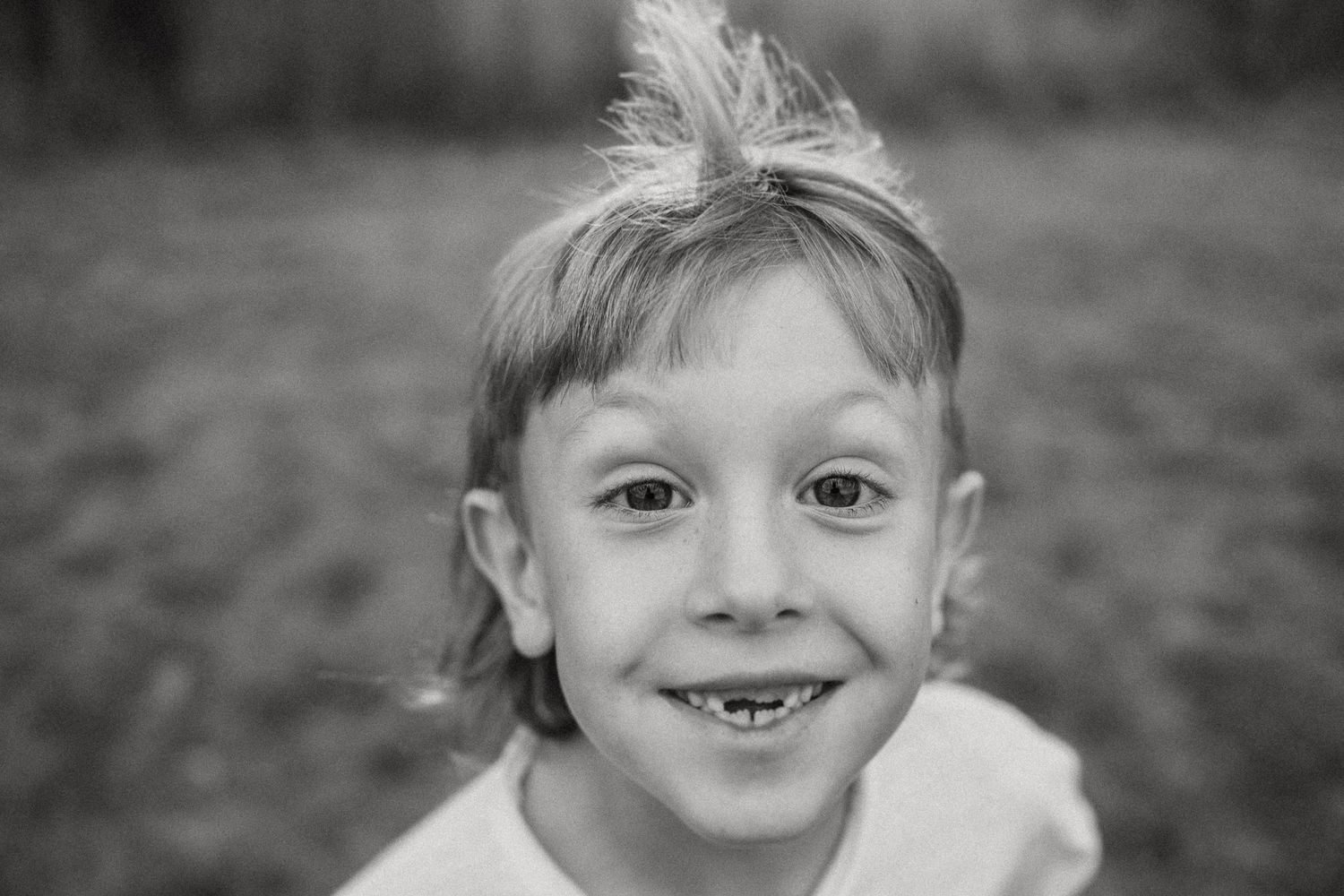 Black and white portrait showing cheerful expression with missing teeth.