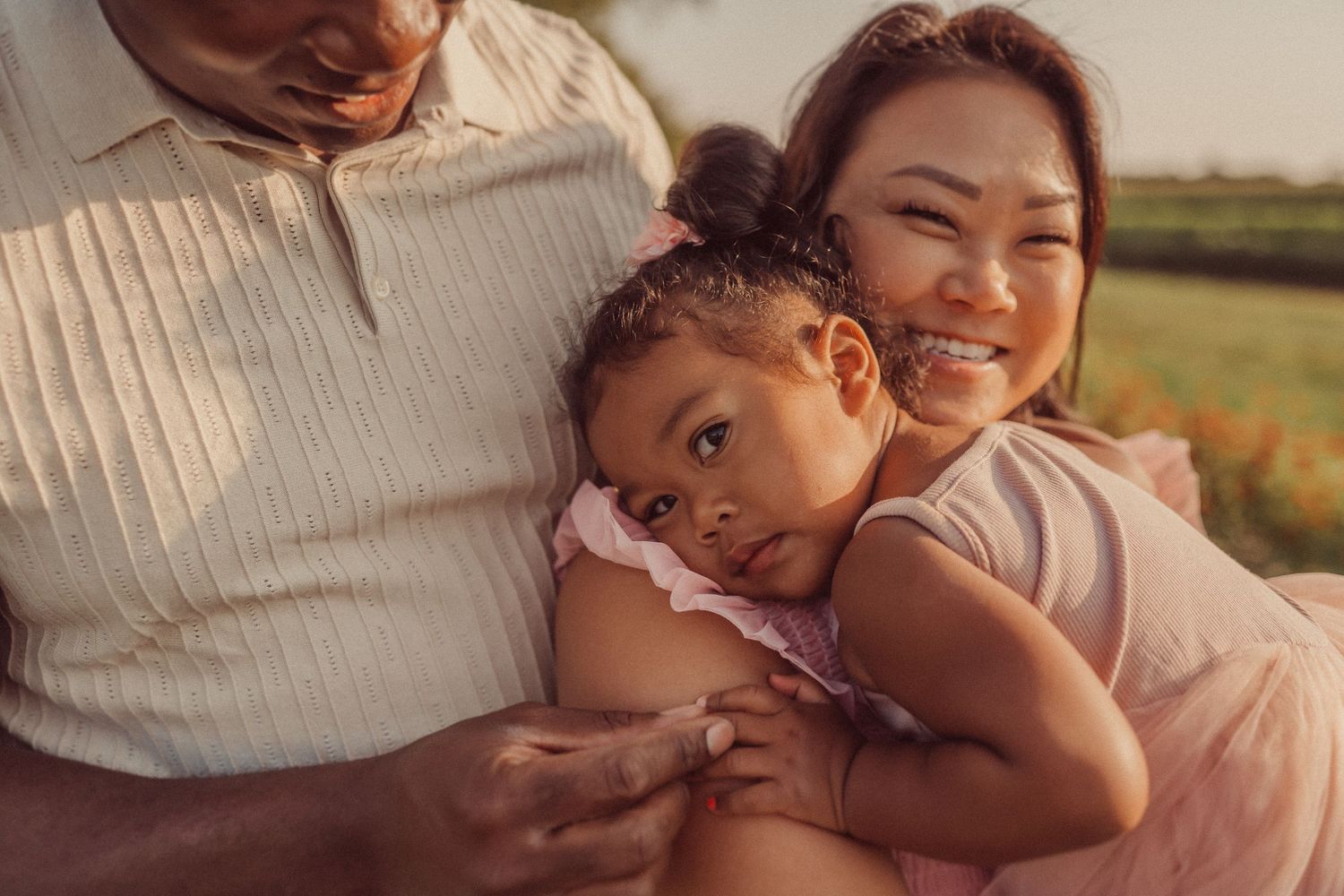 A tender family moment captured in warm evening light outdoors.