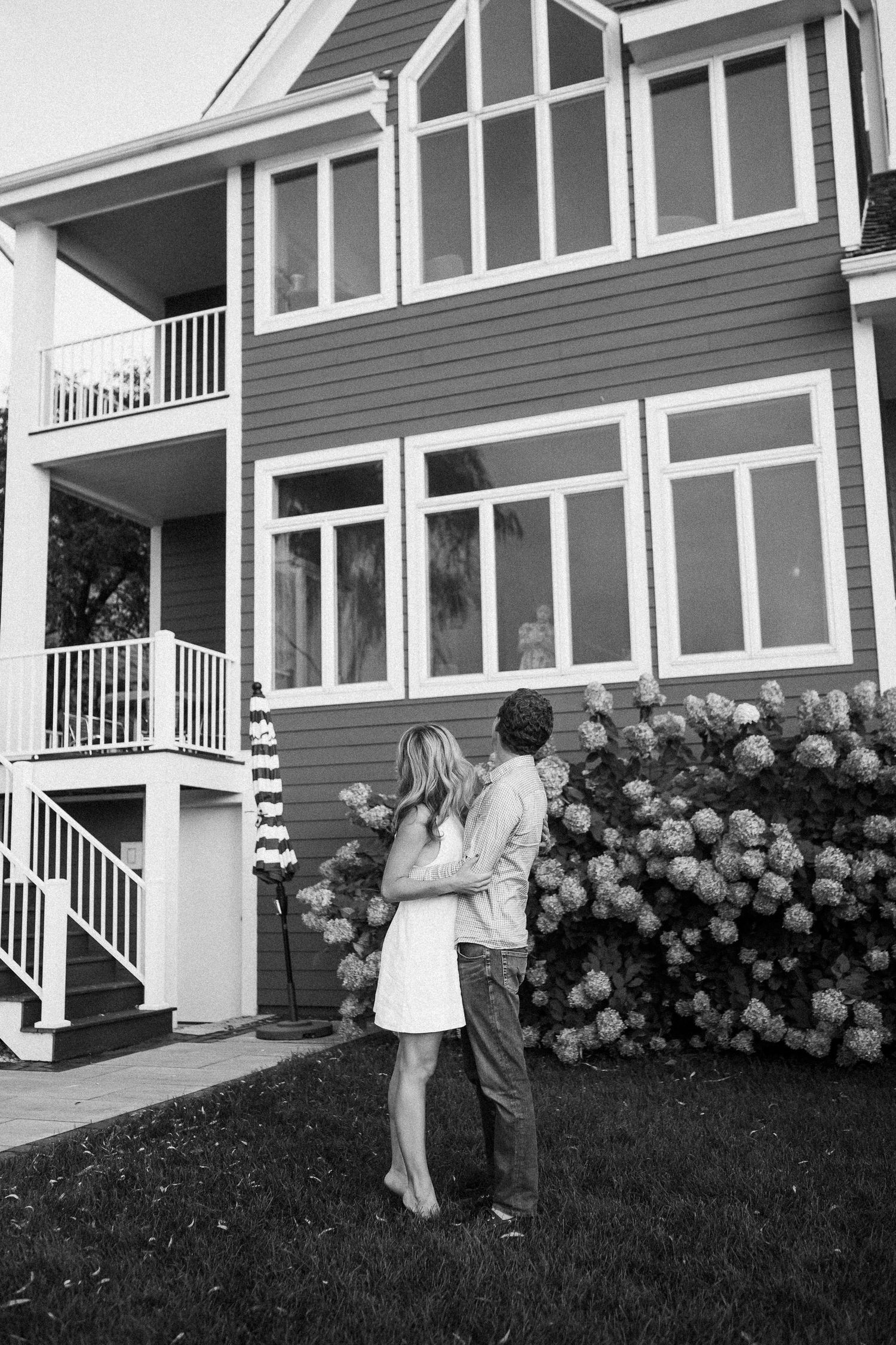 A couple shares a romantic moment dancing on the grass near blooming hydrangeas.