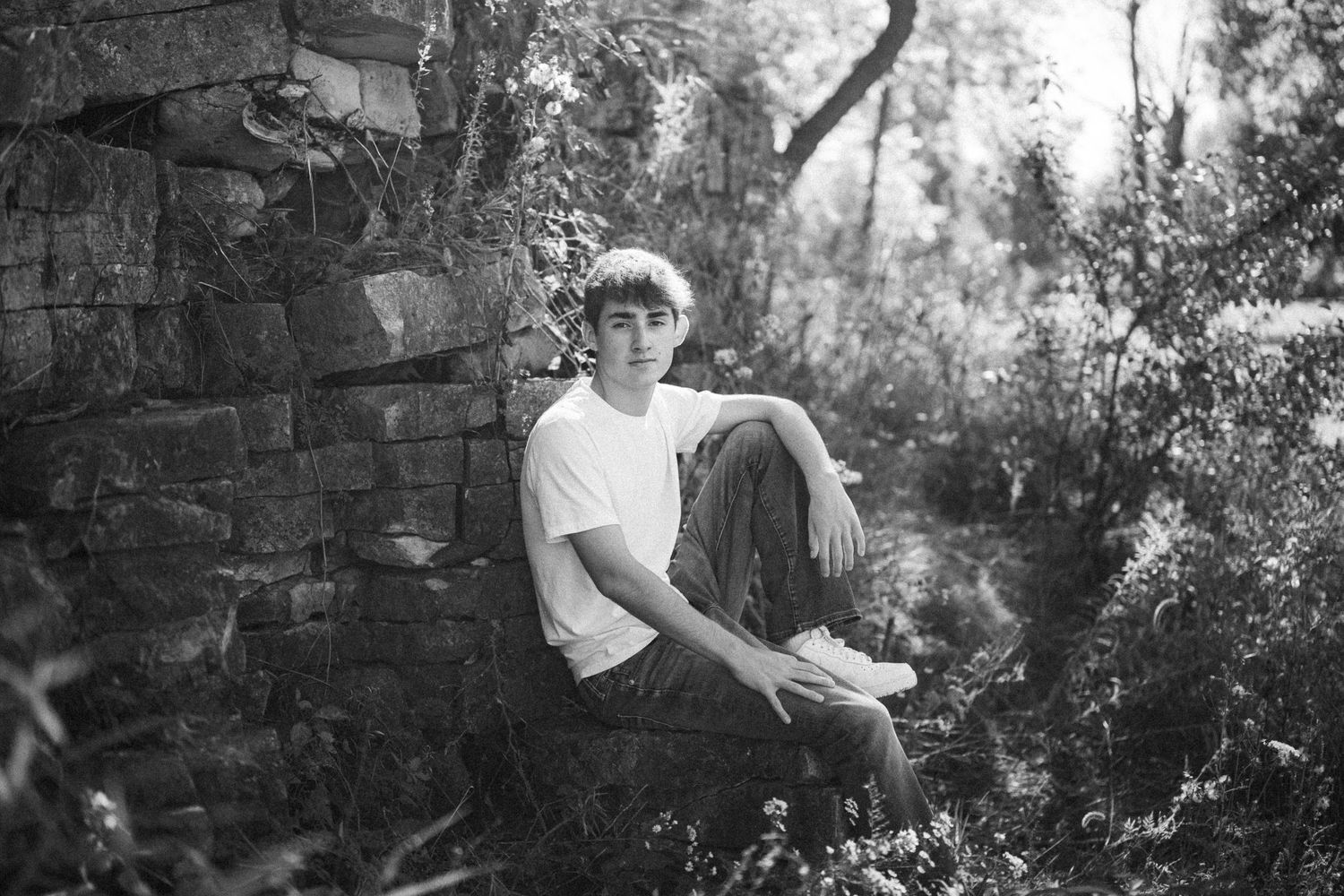 A series of black and white photos showing people relaxing in a garden setting against a stone wall backdrop.
