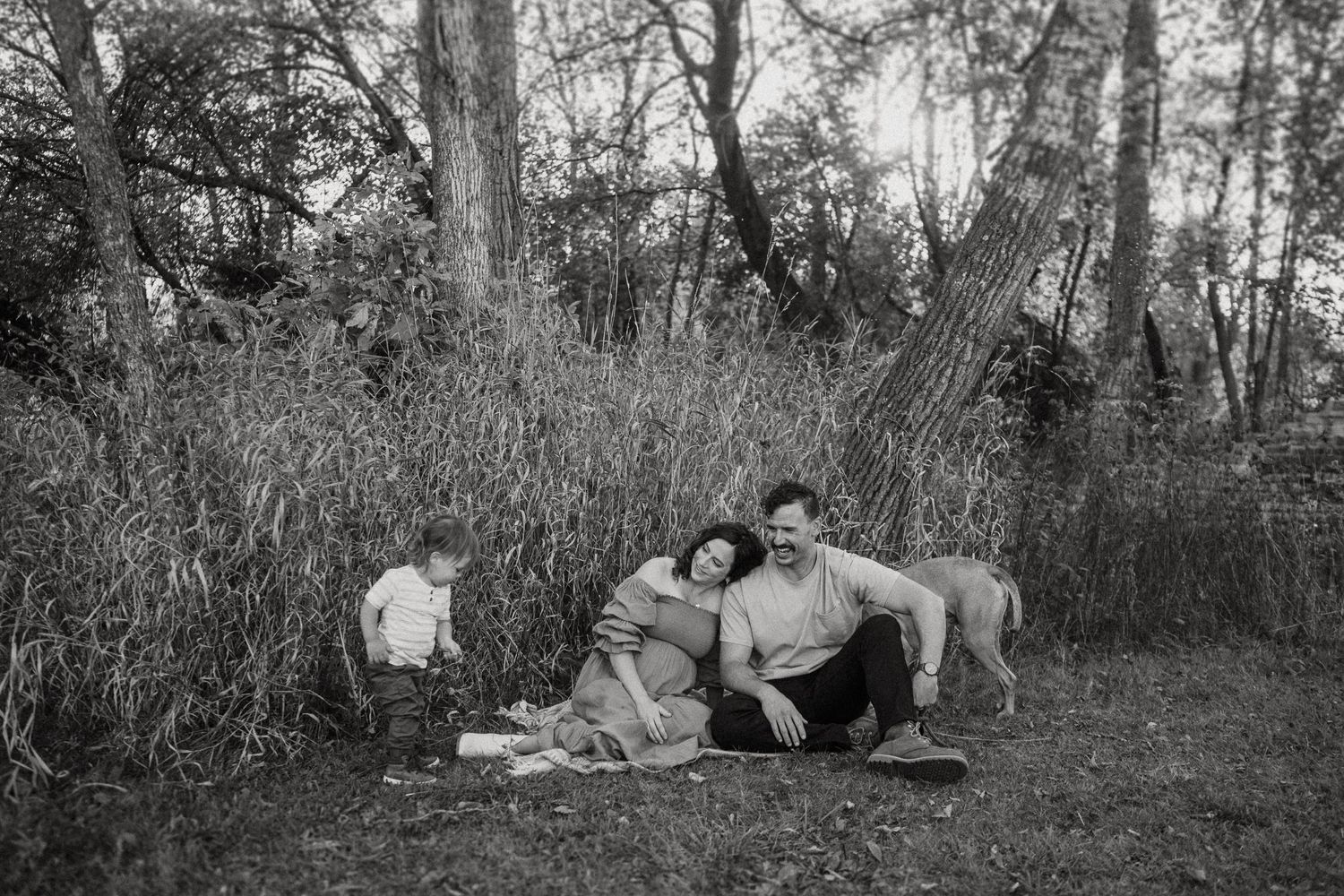 A black and white capture of a family relaxing on a blanket in a natural outdoor setting.