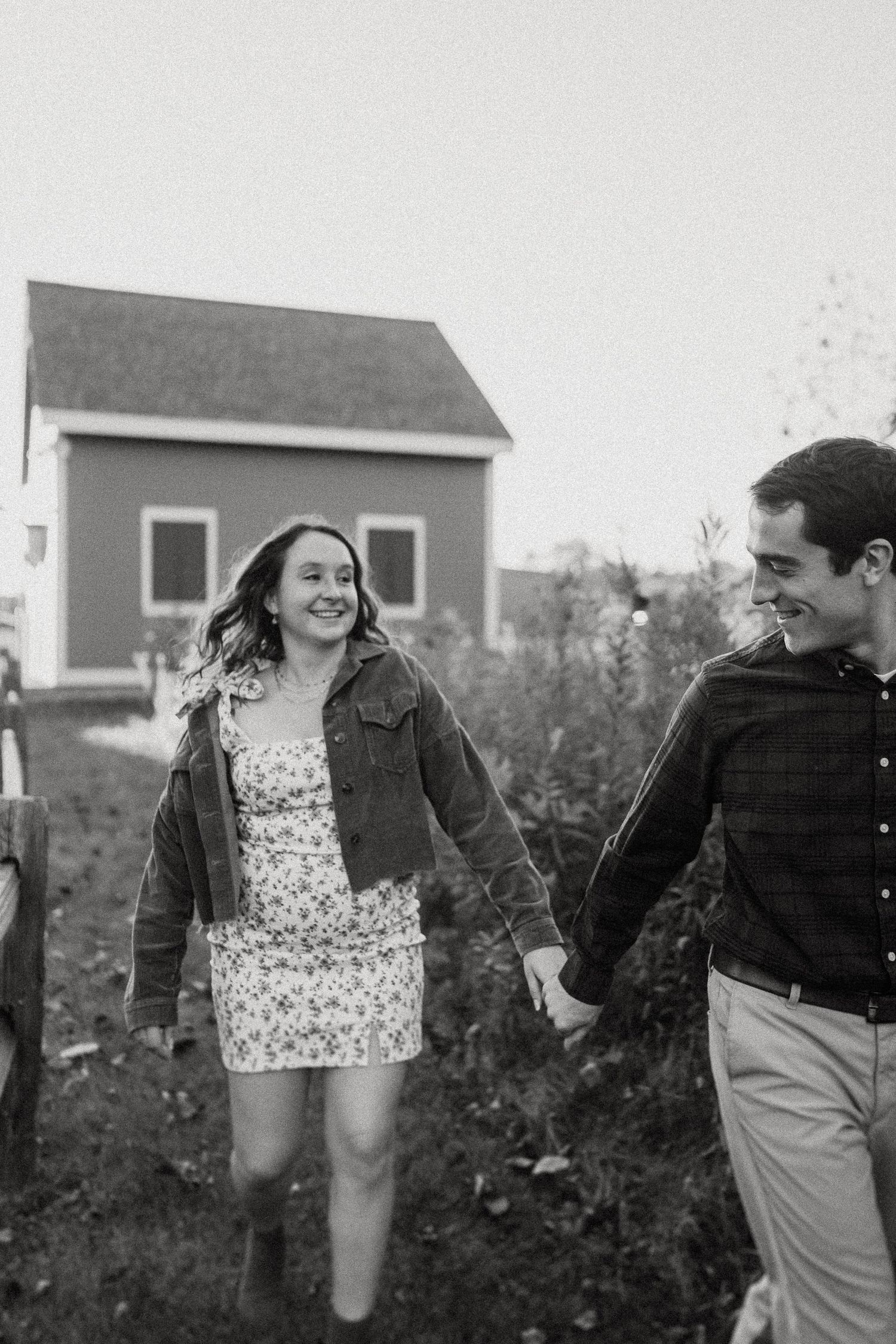 Happy couple running through garden path in black and white photograph.