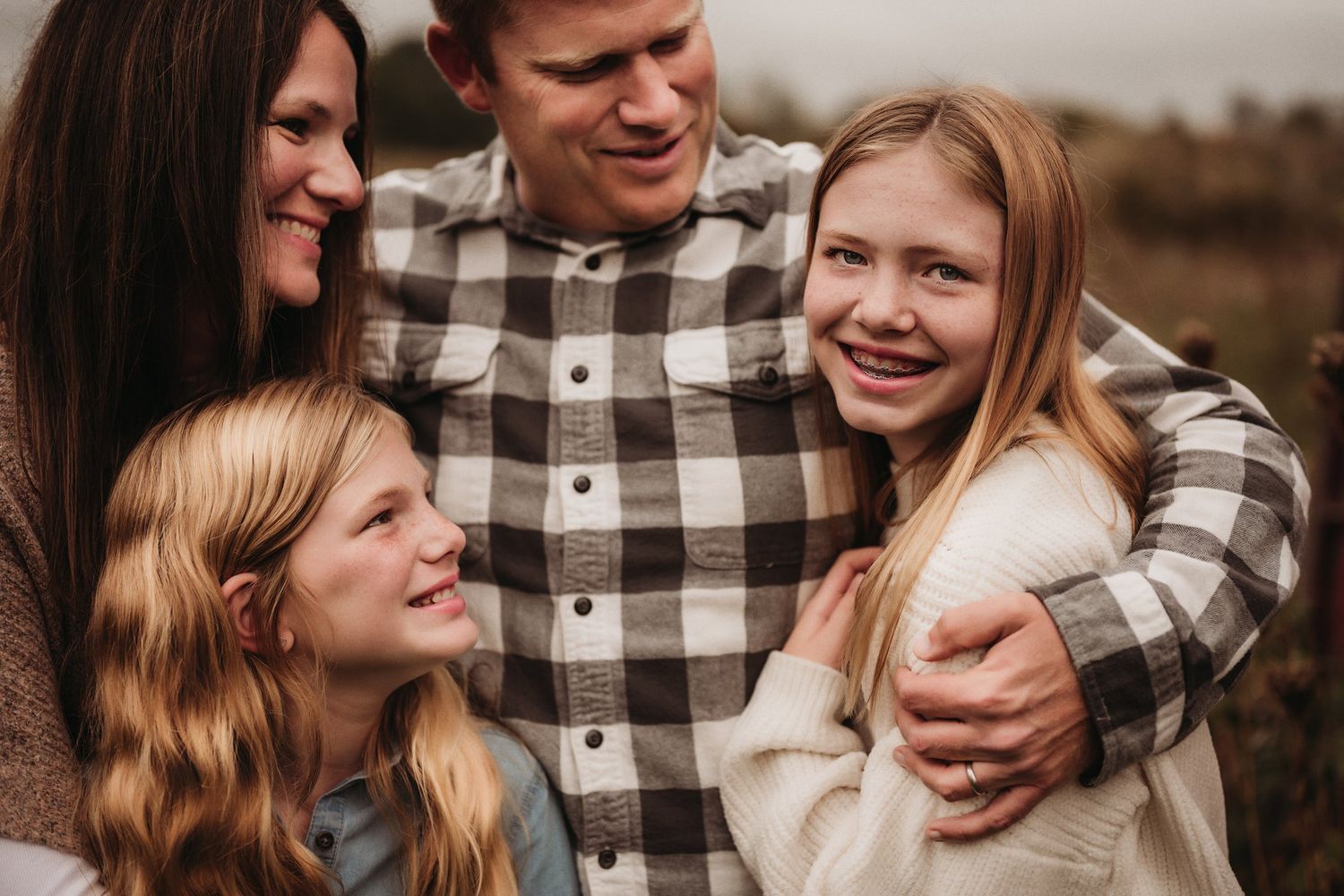 Close-up family portrait showing warm smiles and genuine happiness outdoors.