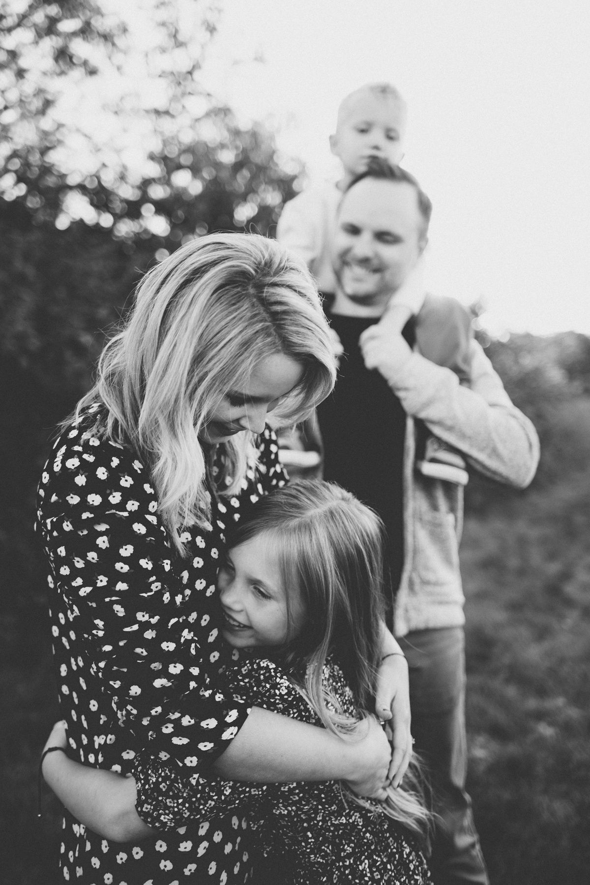 Black and white candid photo of family sharing warm embraces outdoors.