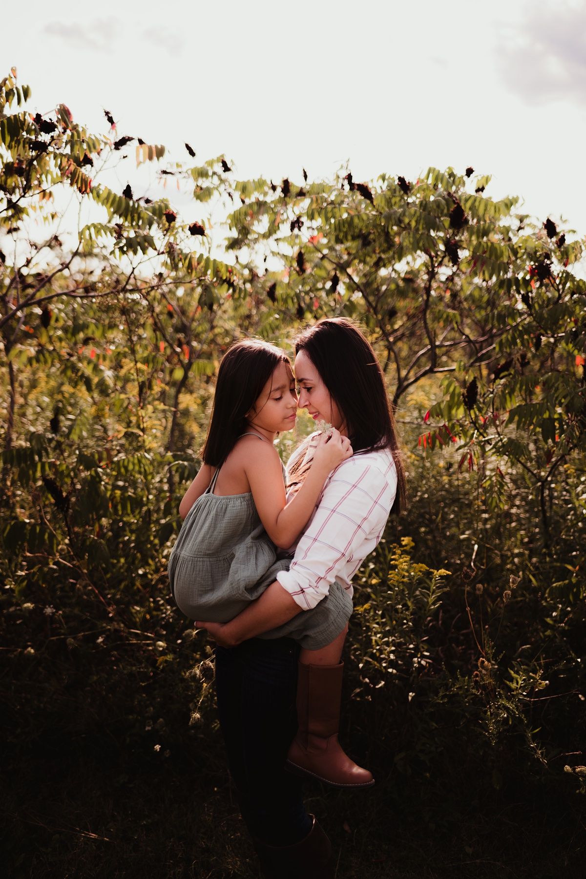 Two people sharing an intimate embrace among autumn foliage at golden hour.