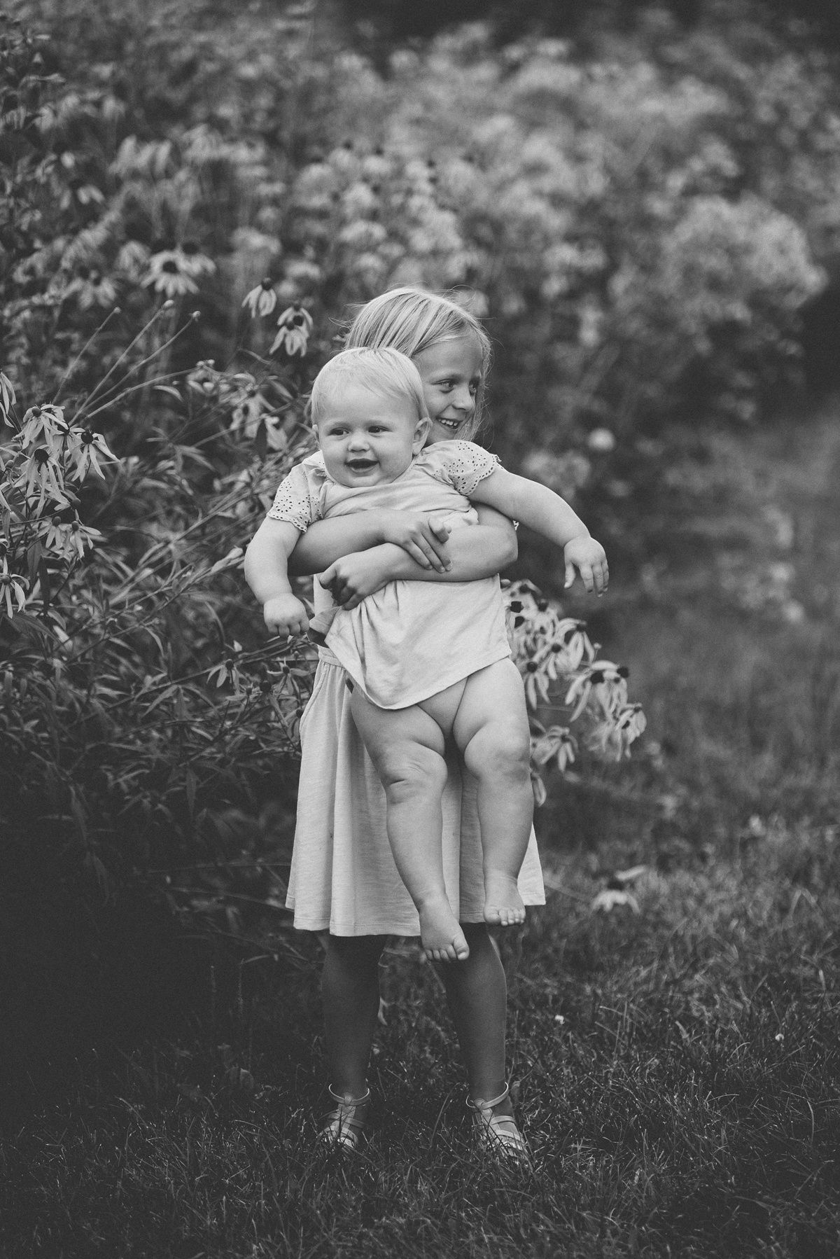 Black and white portrait of children playing together in garden setting.
