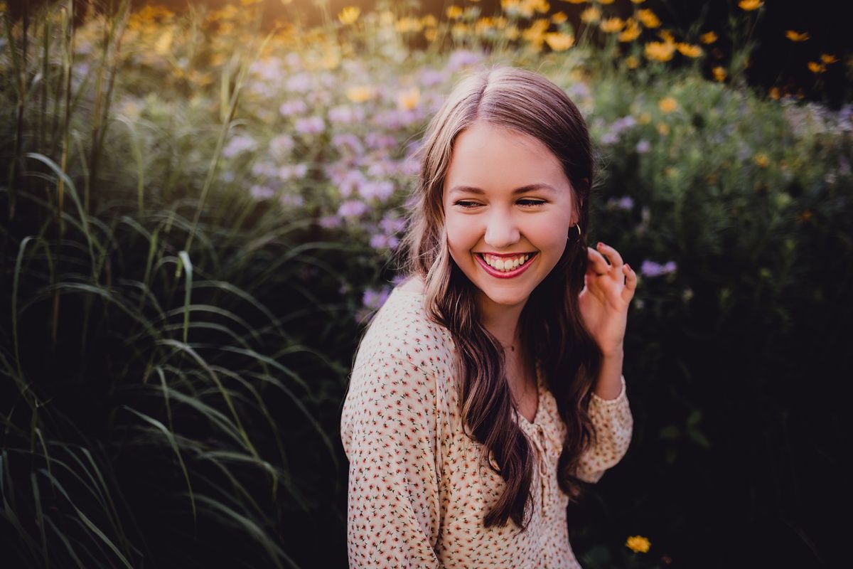 Candid outdoor portrait showing joyful laughter among autumn wildflowers and natural lighting.