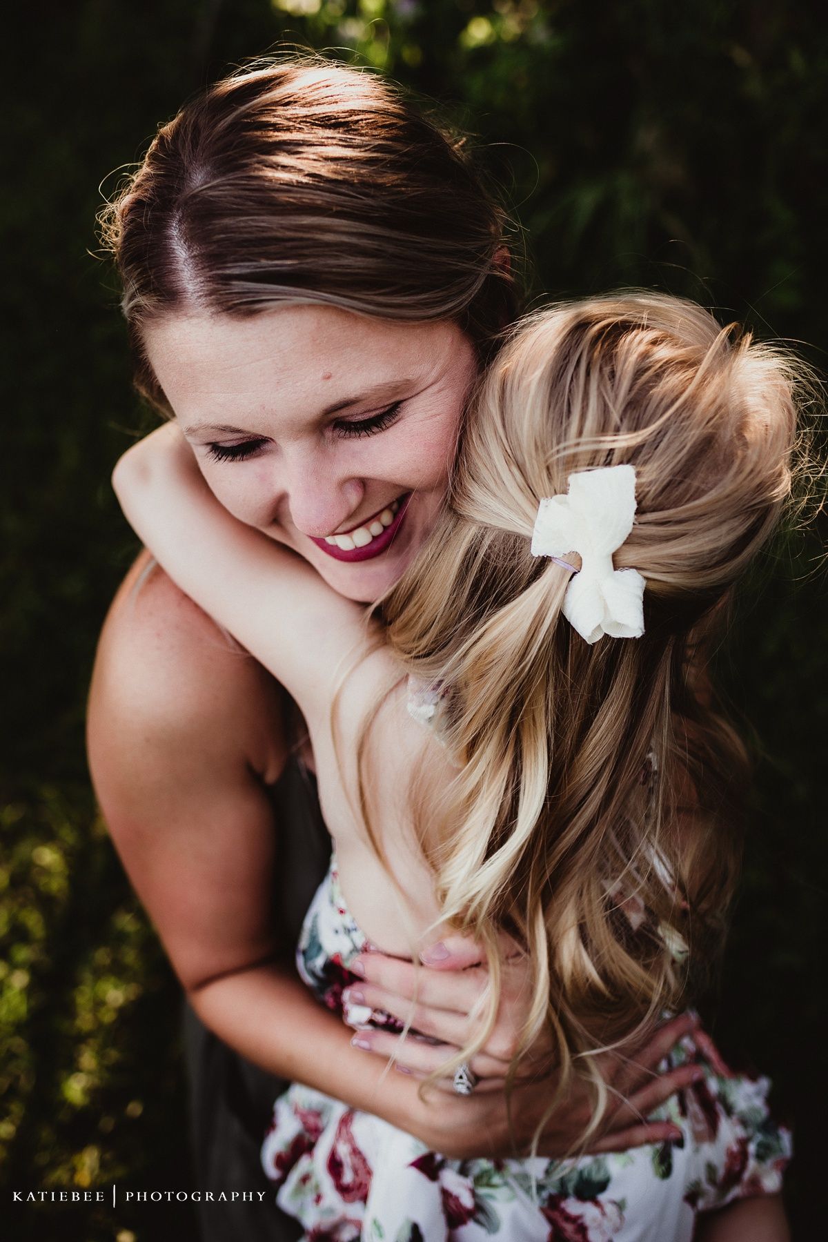 Intimate candid portrait capturing laughter and hugs in a sunlit garden setting.