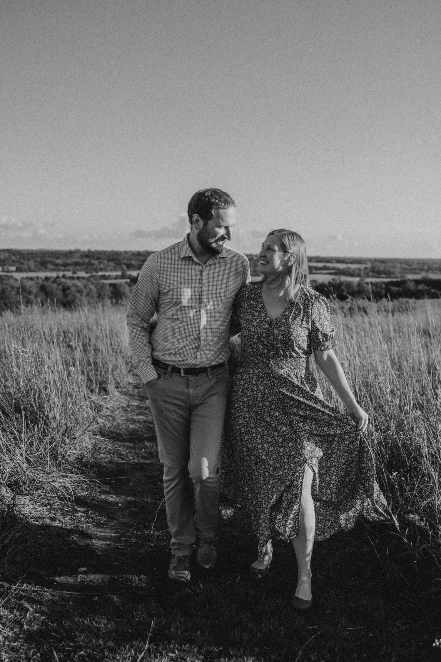Black and white photo of a couple walking together through a rural landscape.