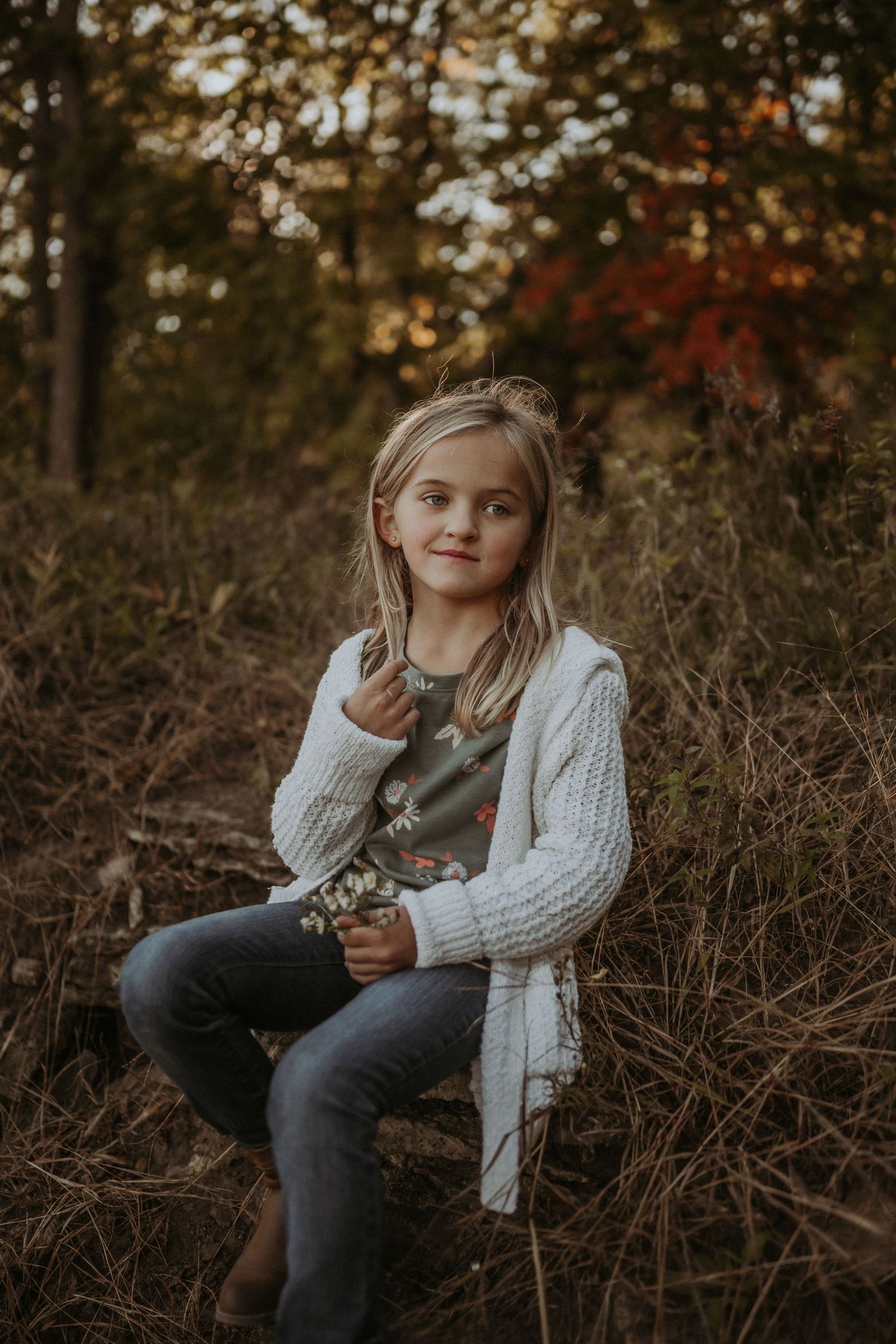 A cozy autumn portrait featuring a white knit cardigan and casual outdoor setting during golden hour.