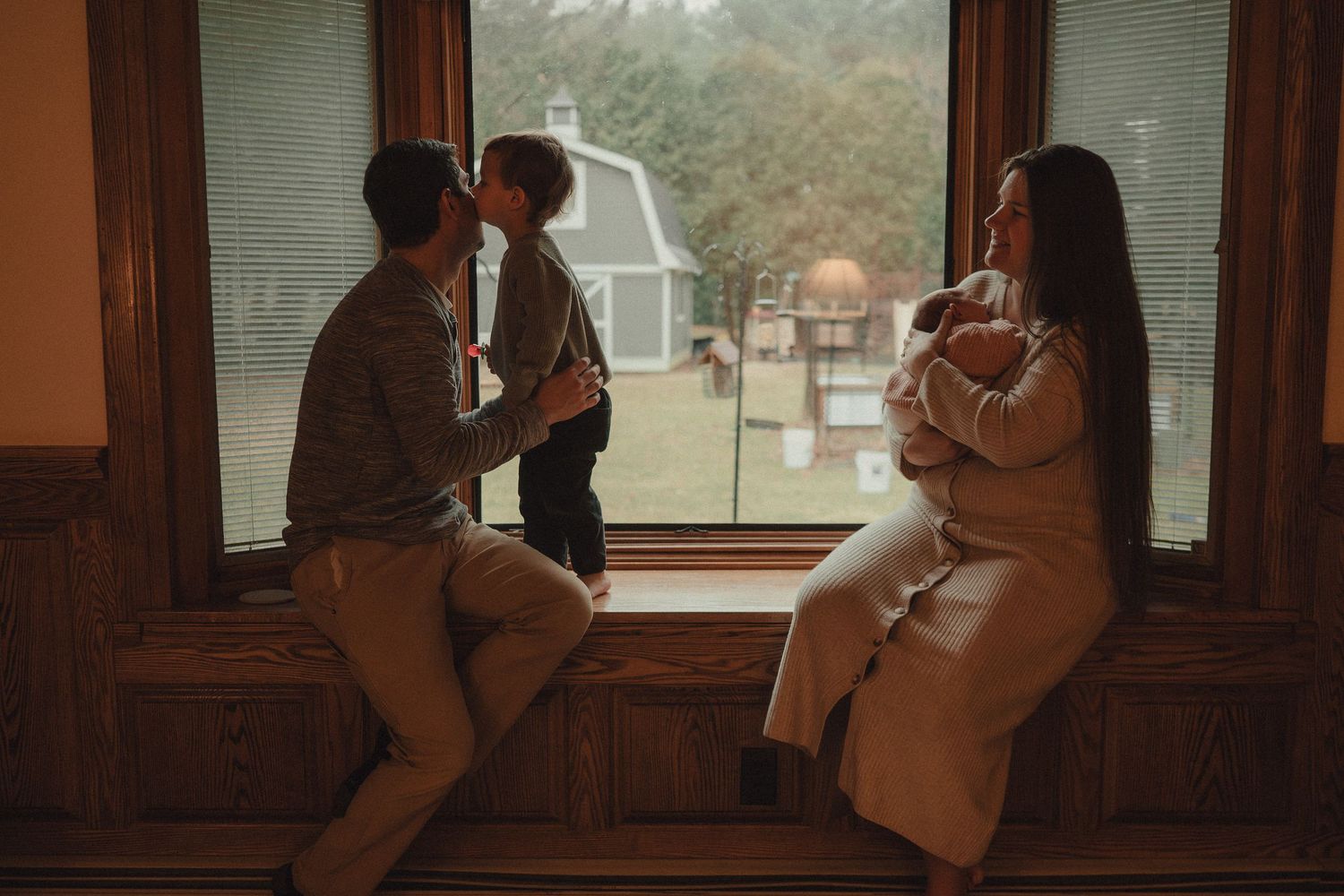A couple dances intimately in a dimly lit room with wooden walls and windows.