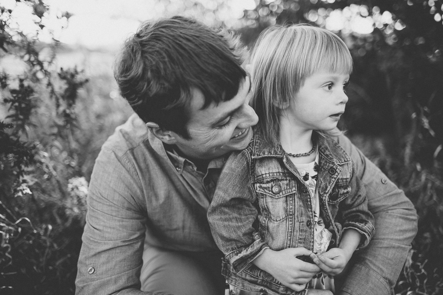 Black and white portrait of tender parent-child moment in outdoor natural setting.