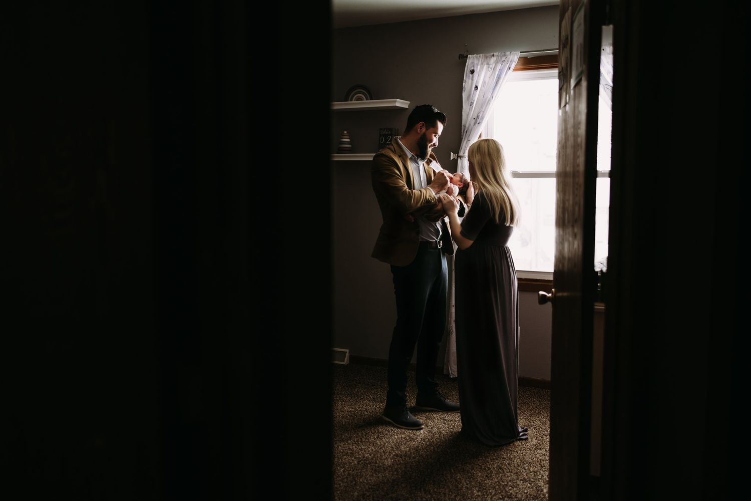 Dark silhouettes of family members standing in doorway near window.