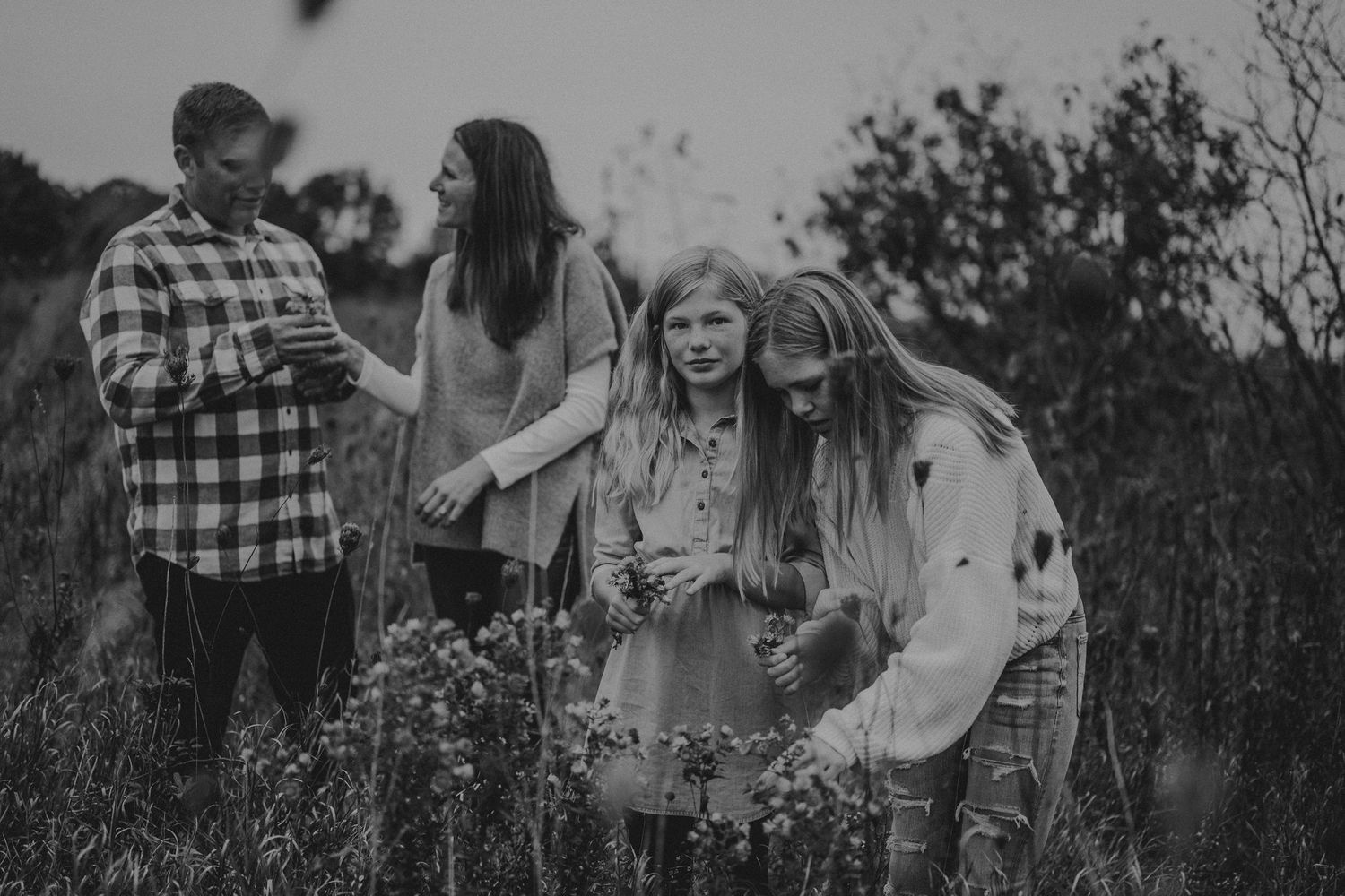 Black and white candid of family gathering in a wildflower meadow.
