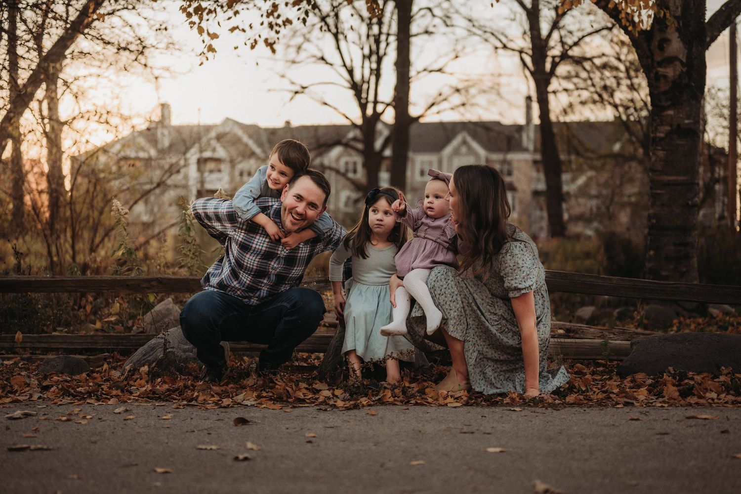 A cheerful group enjoys quality time together on a path covered in fallen autumn leaves.
