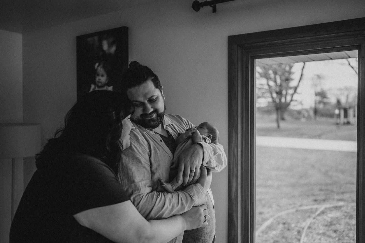 An intimate family moment captured in black and white as parents share joy with their newborn.