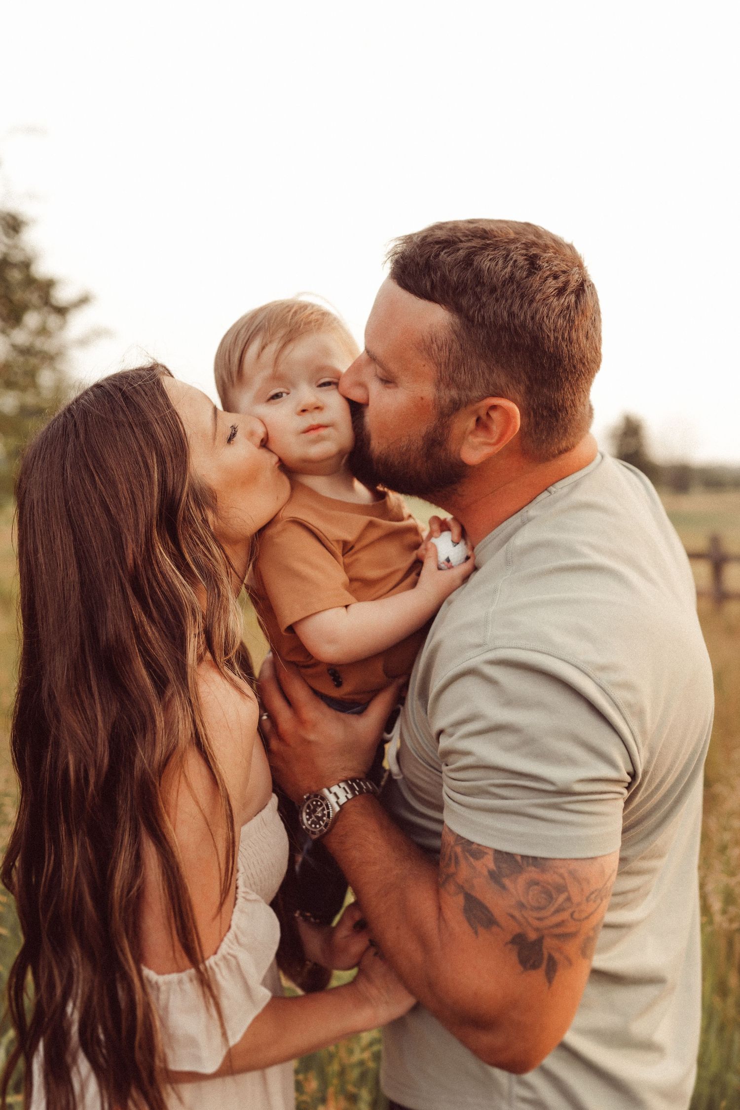 Intimate family portrait during golden hour showing affectionate moments in a pastoral setting.