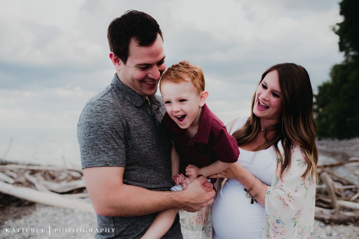 A joyful family moment captured on a beach with driftwood in the background.