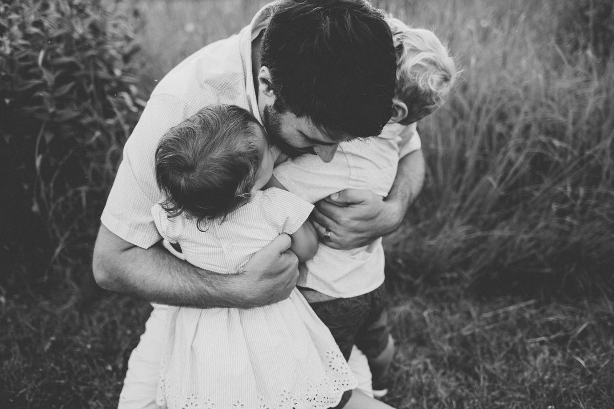 Black and white intimate family moment showing tender embrace outdoors.