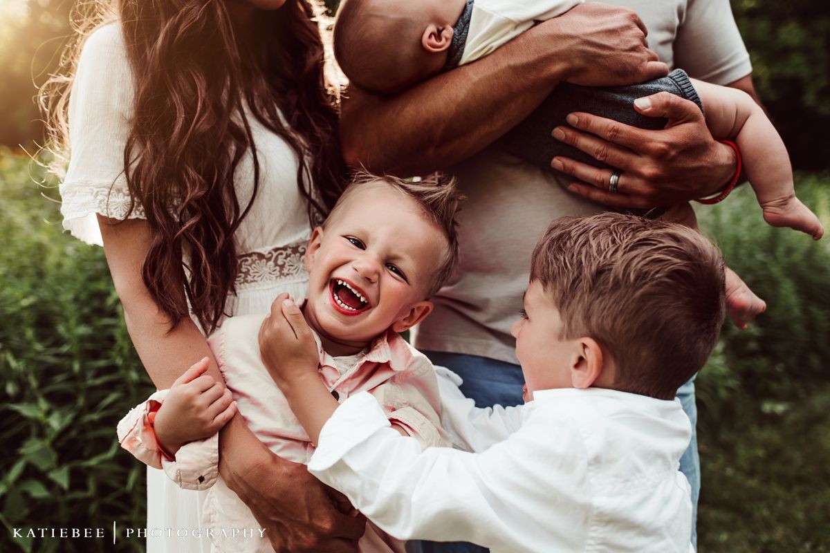 Candid family photograph capturing genuine laughter and joy in a garden setting.