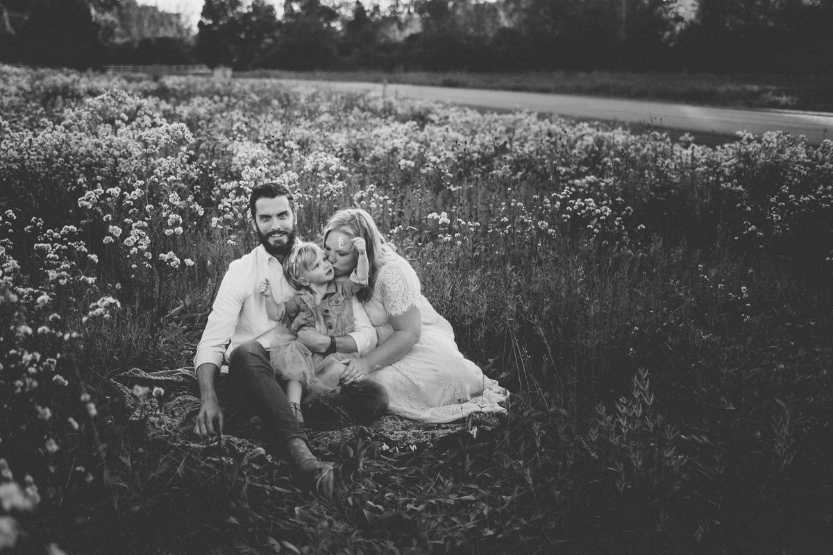 Black and white family photo in a field of wildflowers during golden hour.