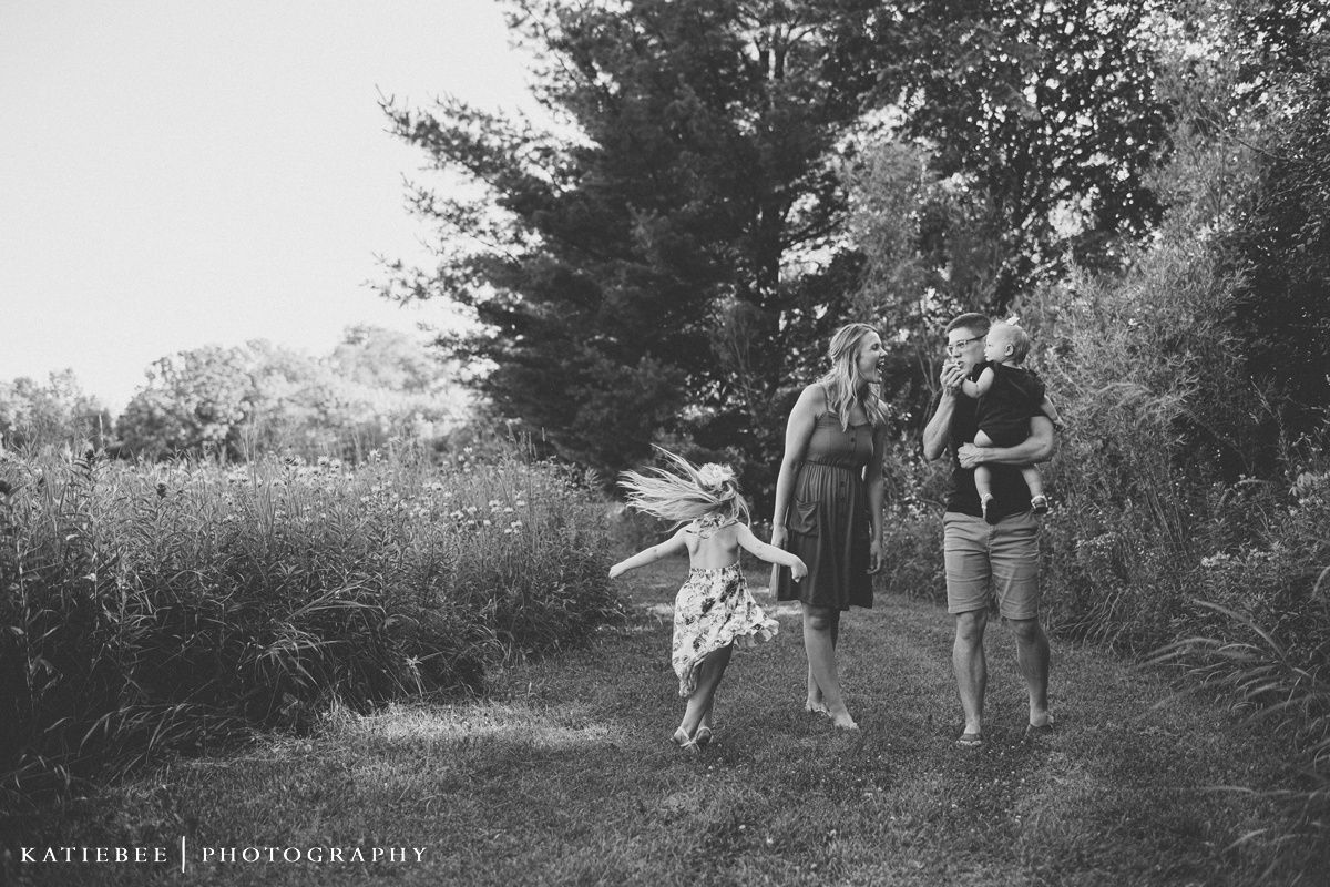 Black and white photograph of family walking together through a meadow.