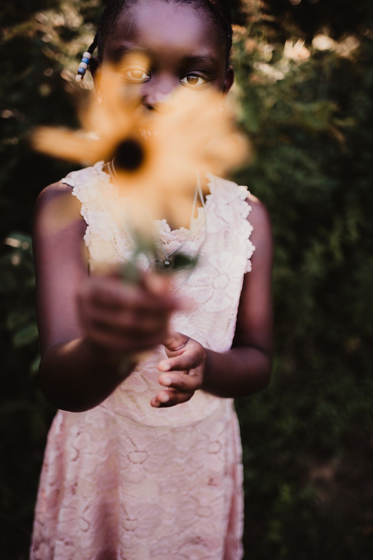 An artistic portrait with selective focus on flowers in the foreground against a natural backdrop.