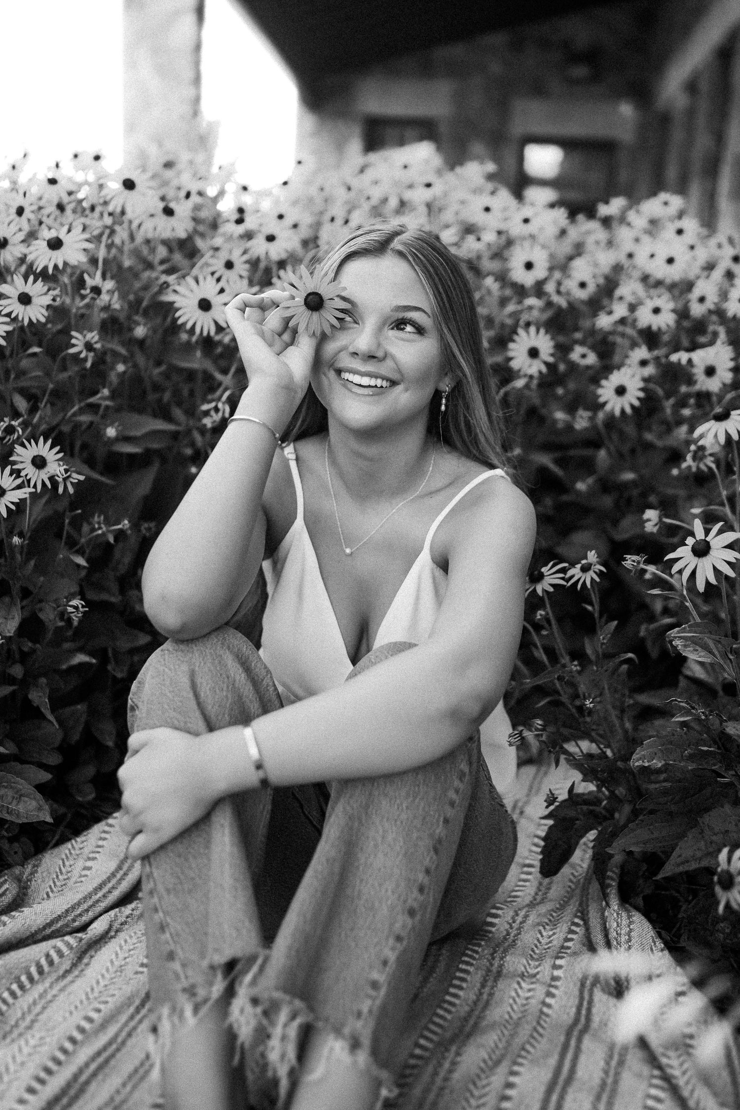 Black and white portrait surrounded by blooming daisies in a garden setting.