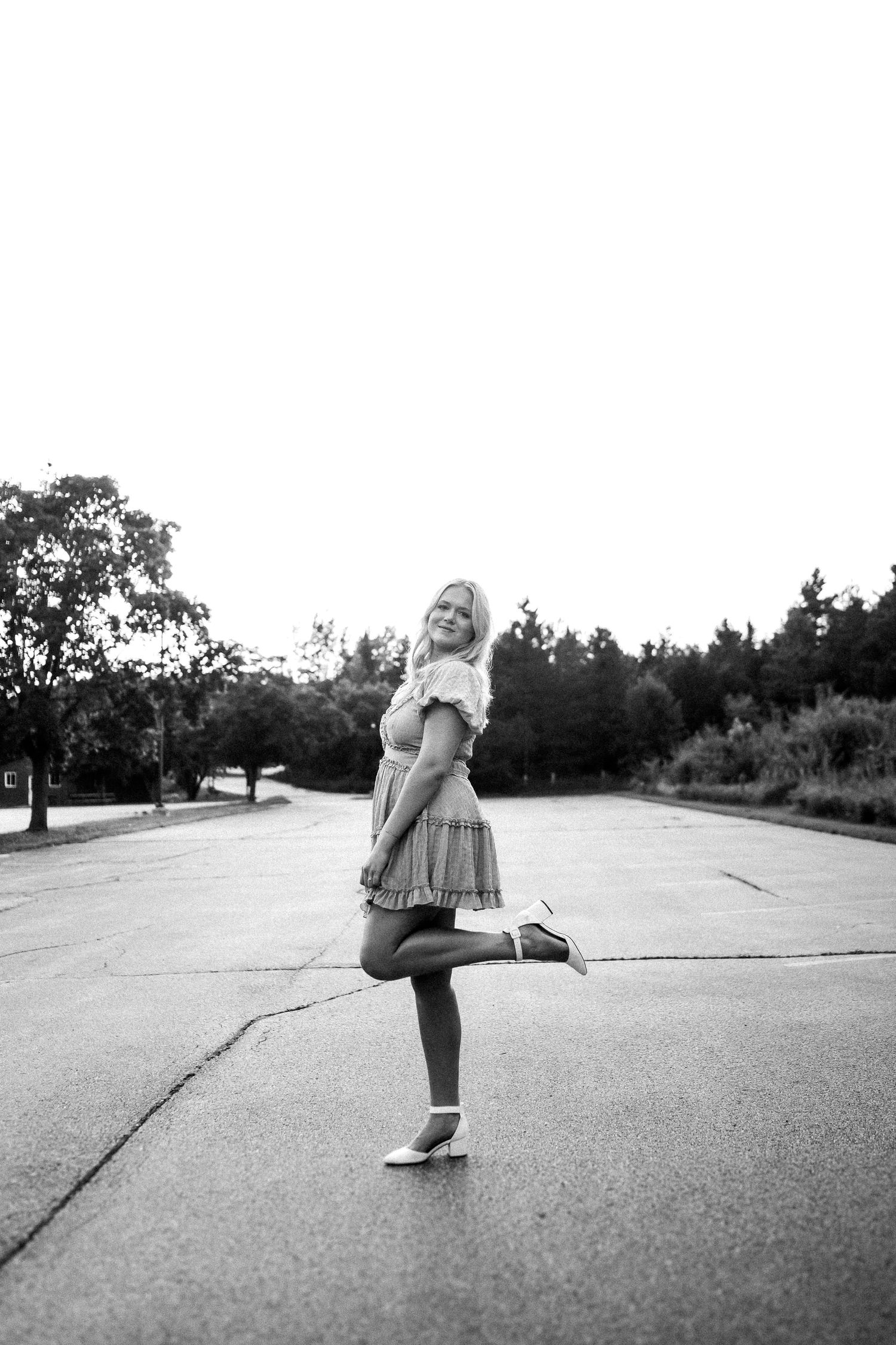 Dancing figure in dress on concrete surface captured in black and white photography.