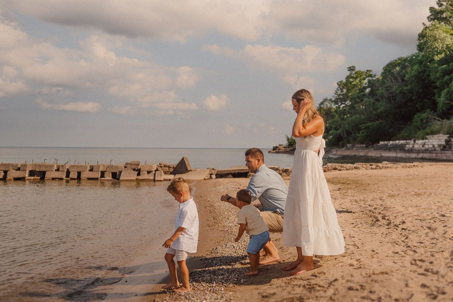 Family enjoying time together on a serene beach with pier visible in background.