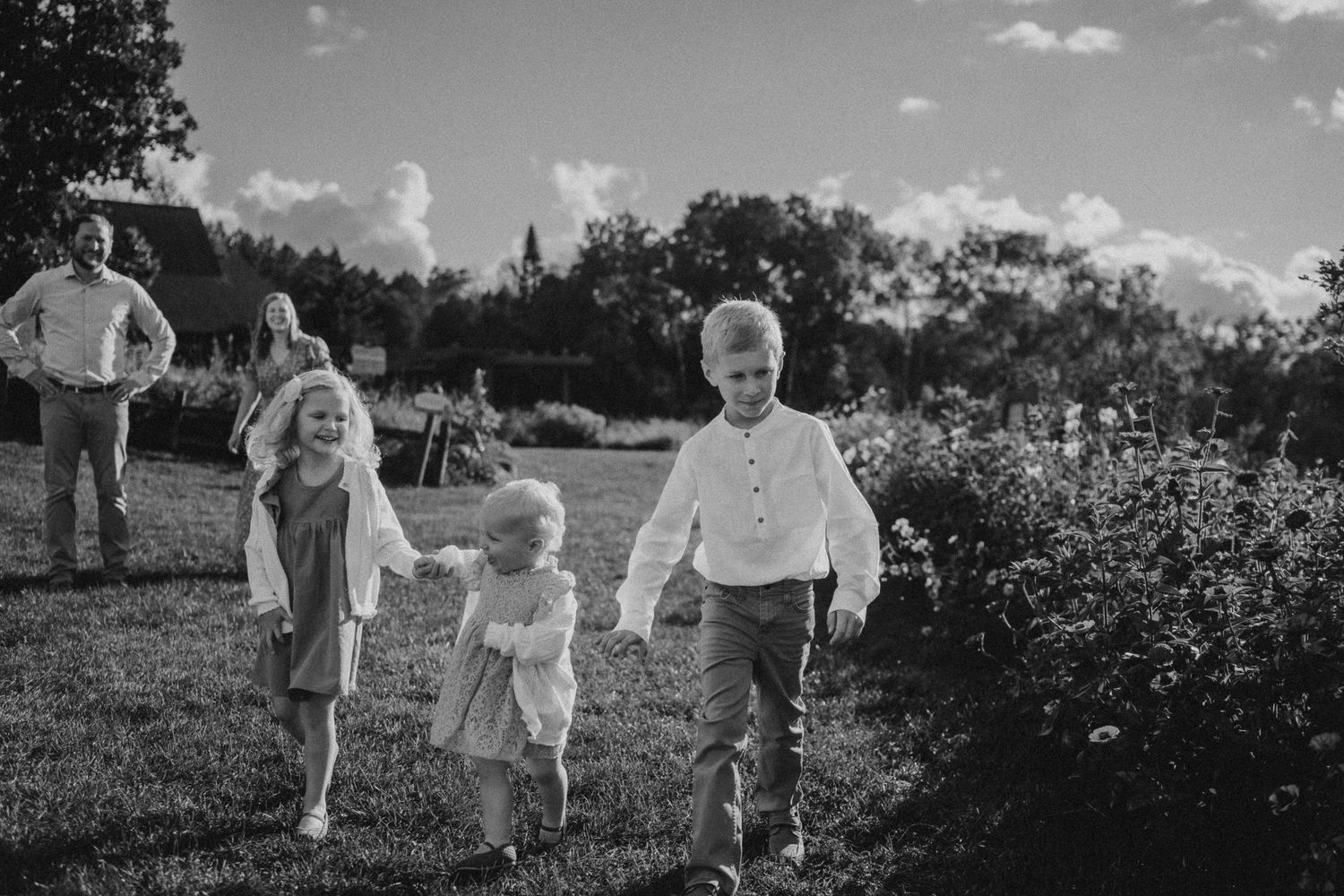 A black and white image of people walking together through a garden landscape.