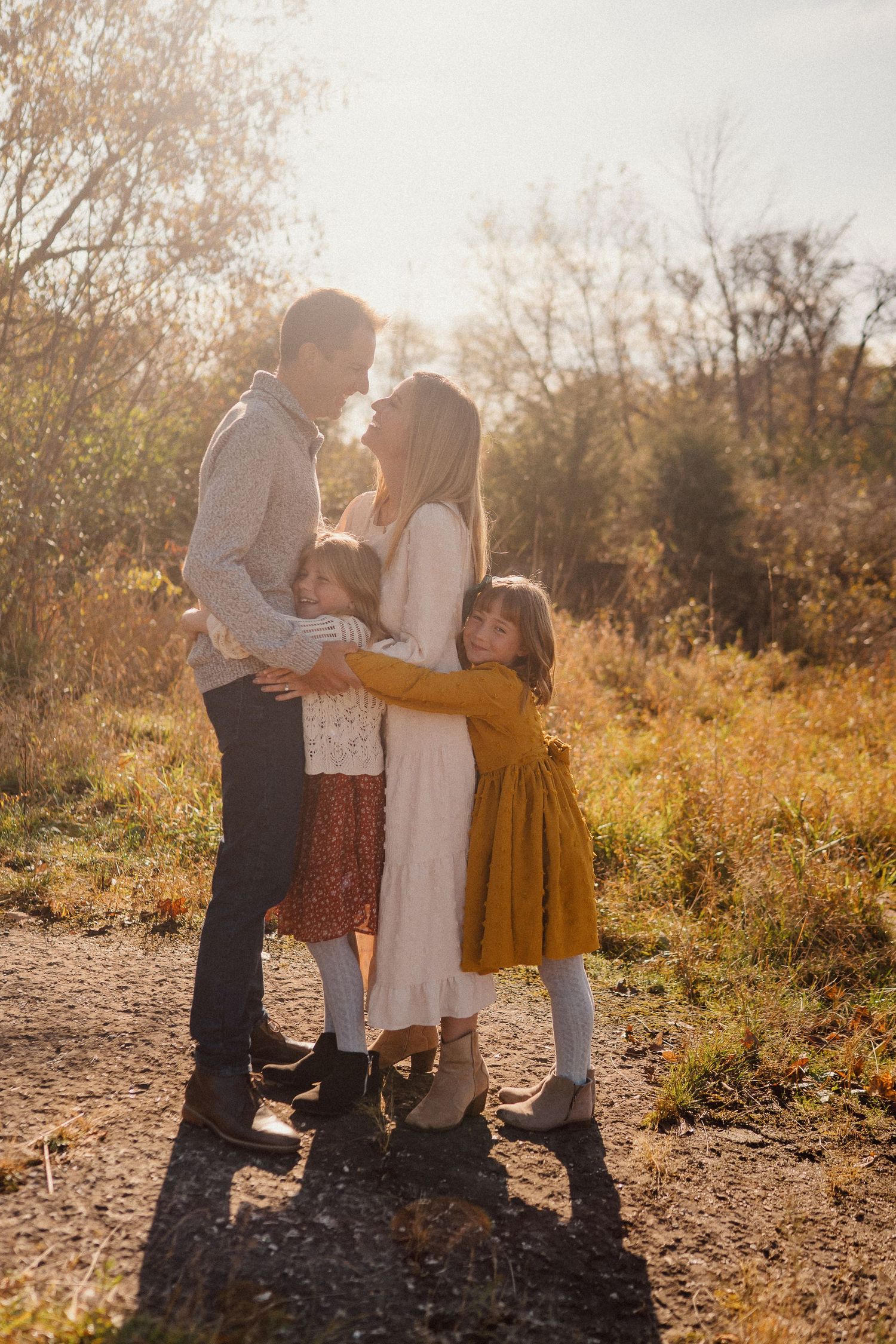 A family enjoys a tender moment together in a golden autumn field at sunset.