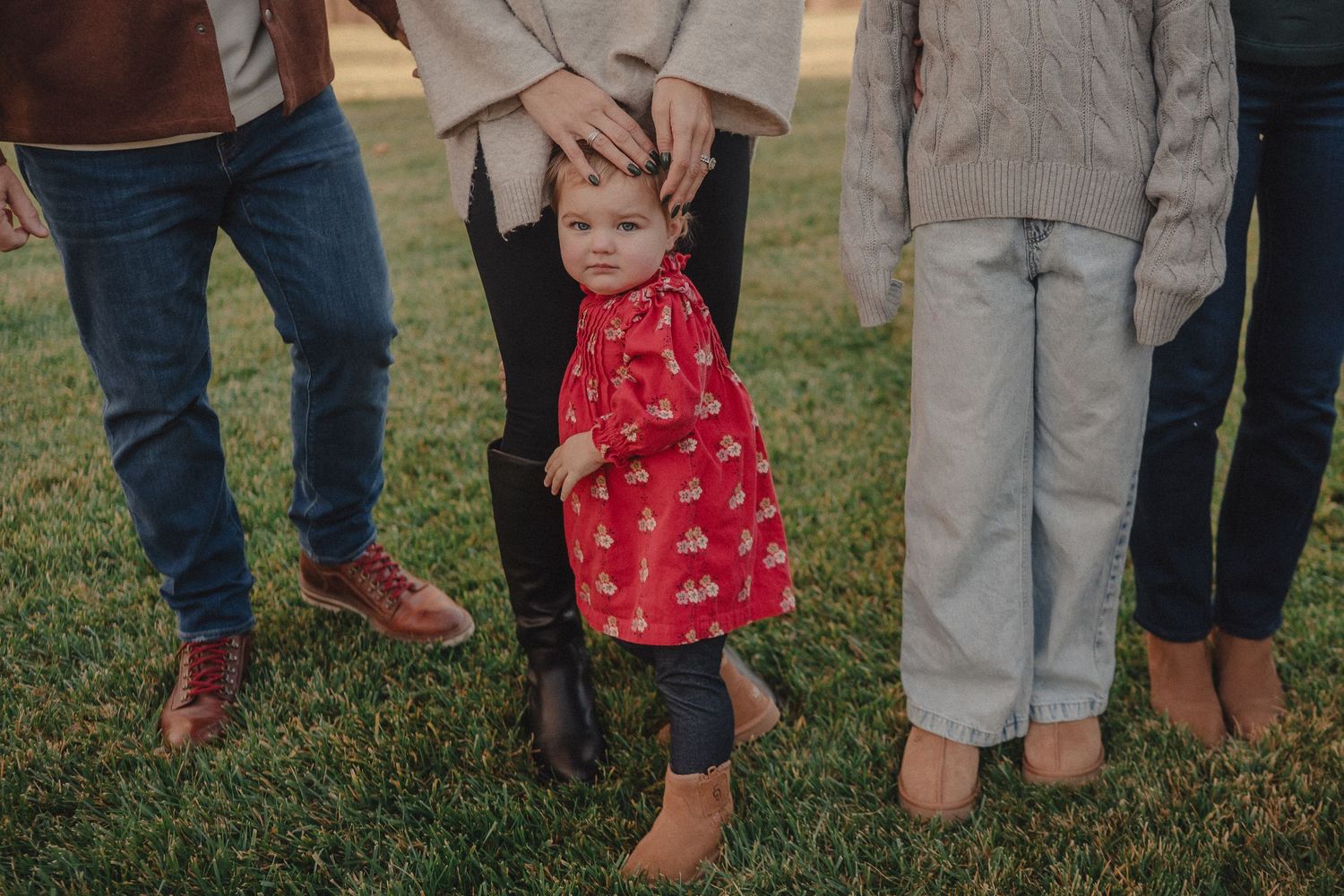 Family members' feet and legs shown standing close together outdoors.