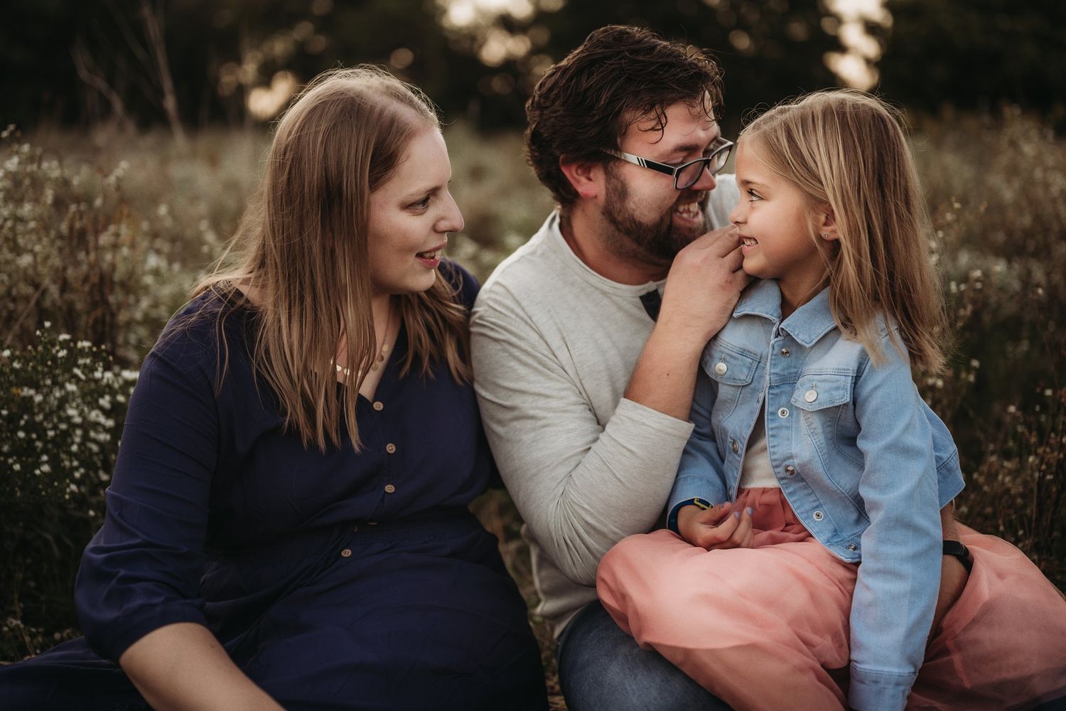 Intimate family portrait session in a natural outdoor setting with wildflowers.