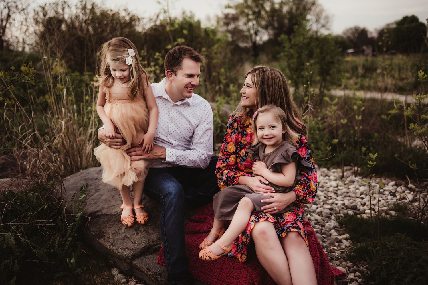 Candid outdoor portrait session on a rustic rock formation surrounded by natural foliage.