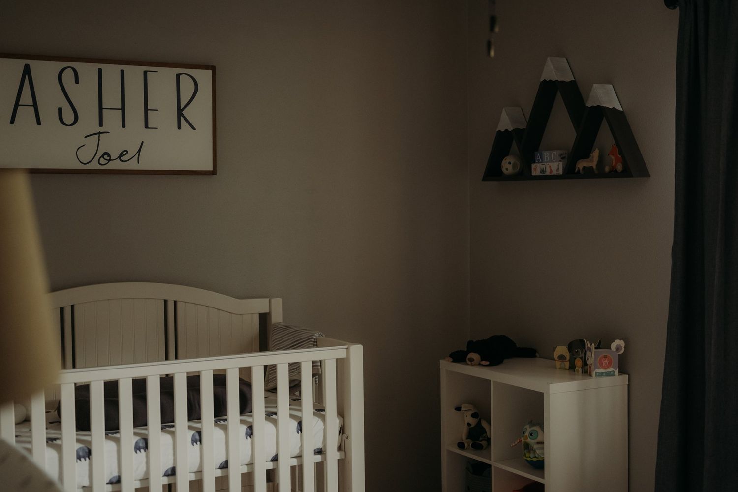 Modern nursery room with white crib, wall decor, and storage furniture.