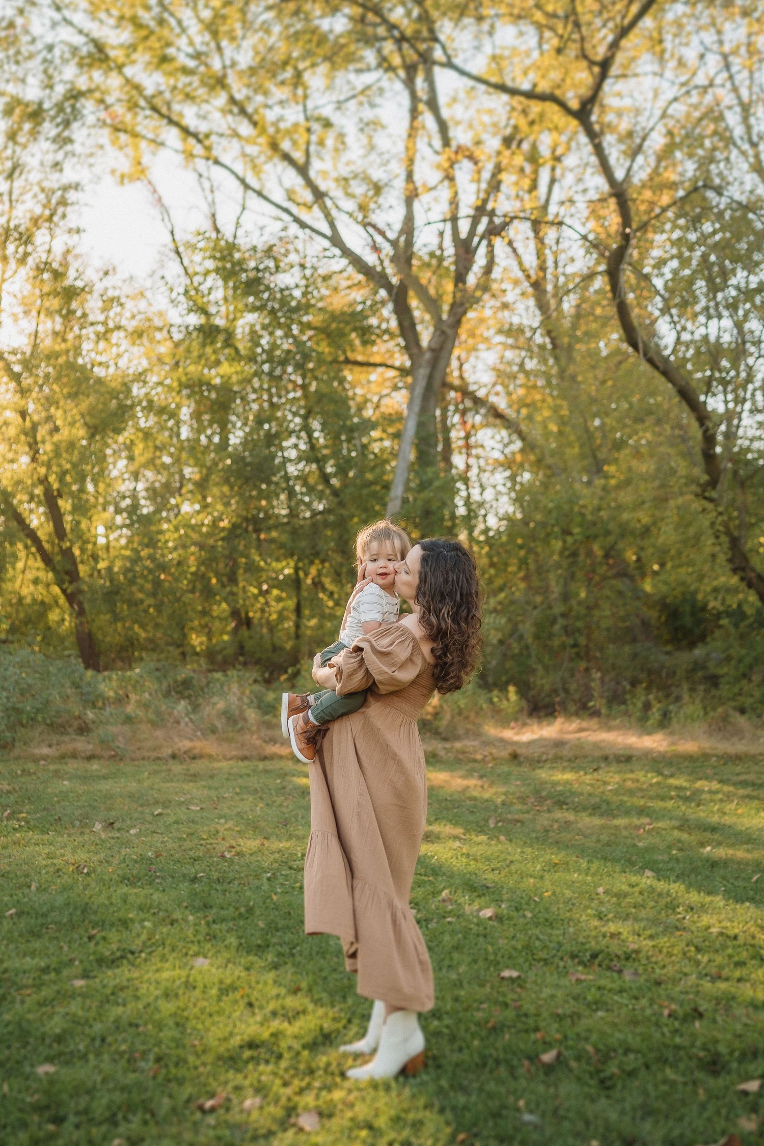 Beautiful autumn scene of tender family moment in a park with golden sunlight filtering through trees.