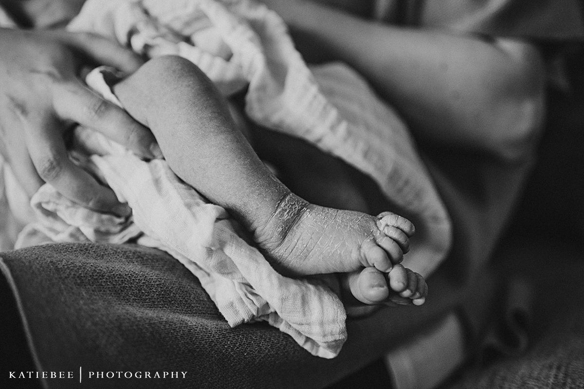 Black and white detail of tiny newborn baby feet and hands.