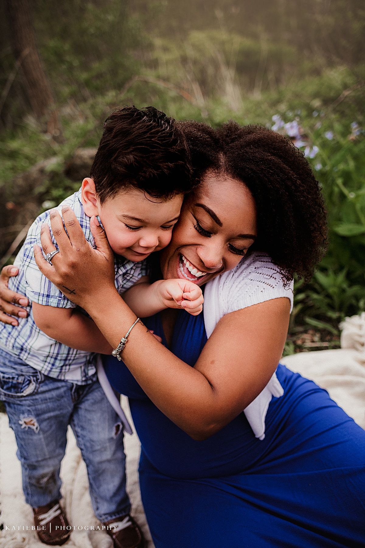 Joyful candid moment between mother and child hugging and laughing in a natural setting.