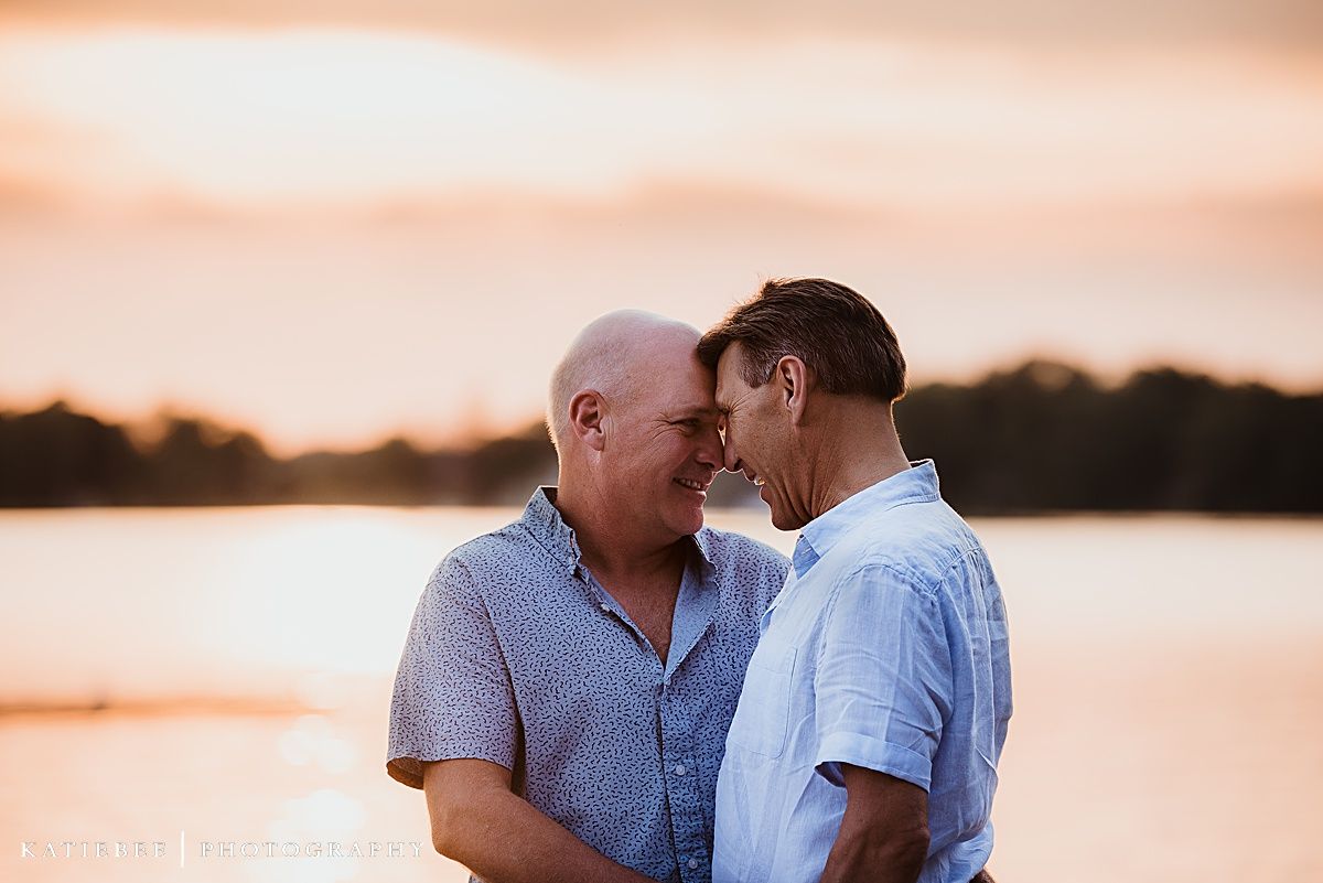 Two people sharing an intimate moment at sunset by the lake.