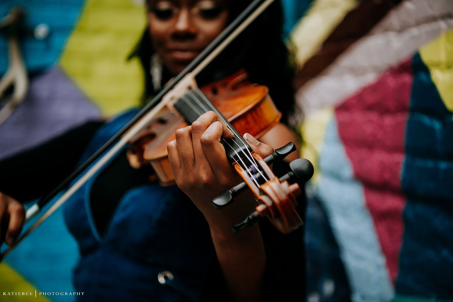 Close-up shot playing violin against colorful street art background.