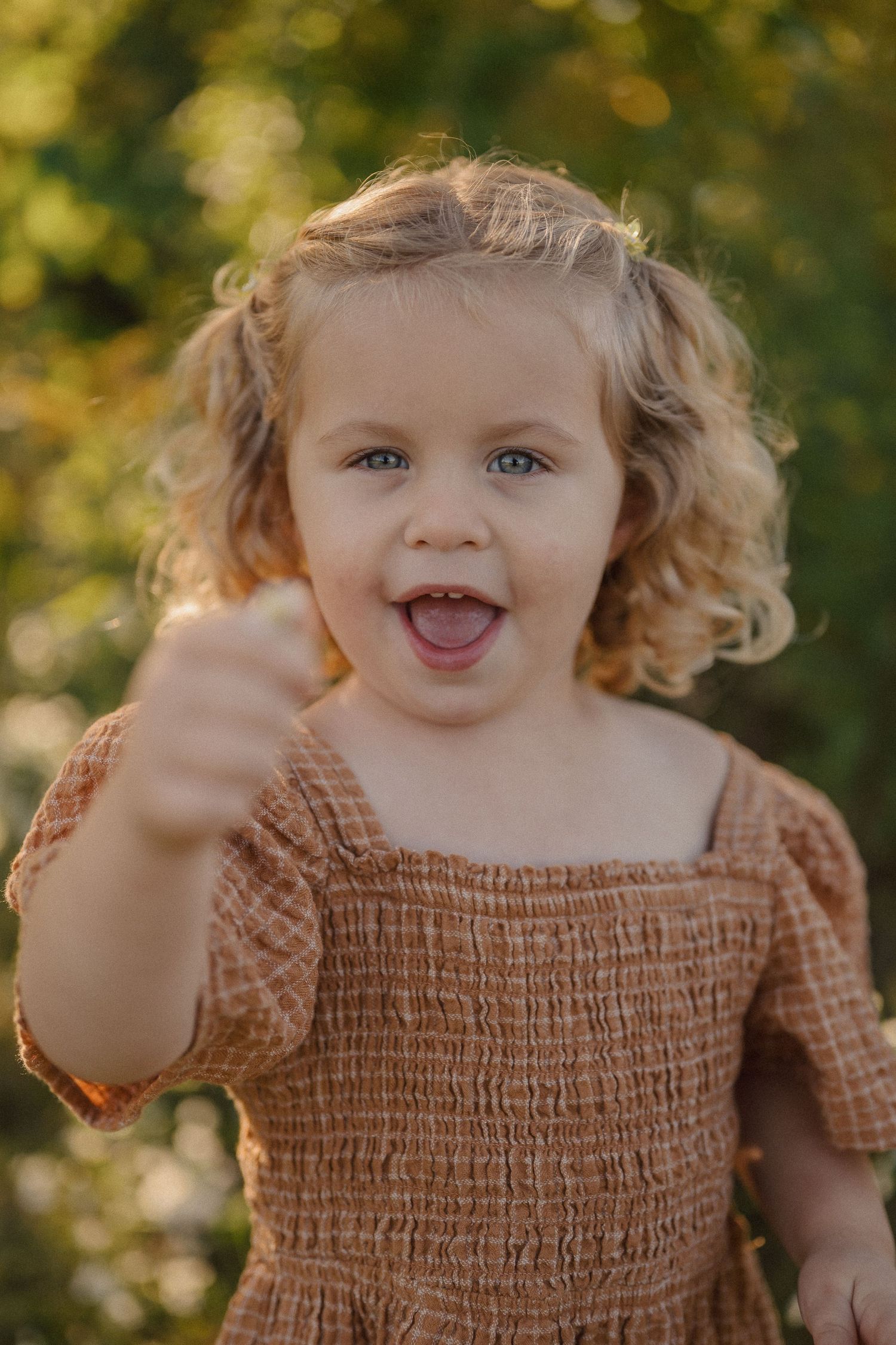 Close up portrait of a child wearing a brown smocked top in autumn sunlight.