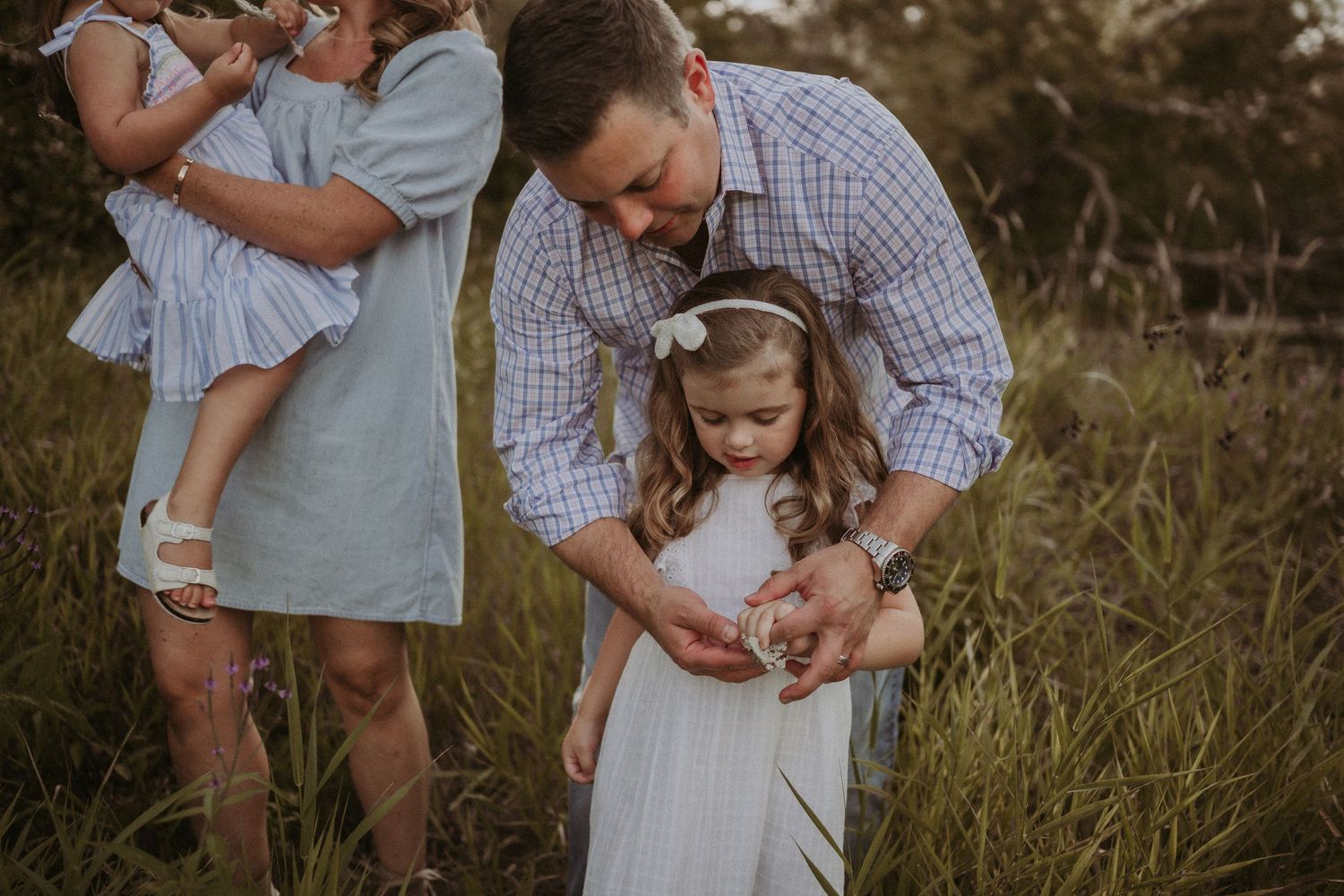 A sweet intimate family moment captured in a field during golden hour.