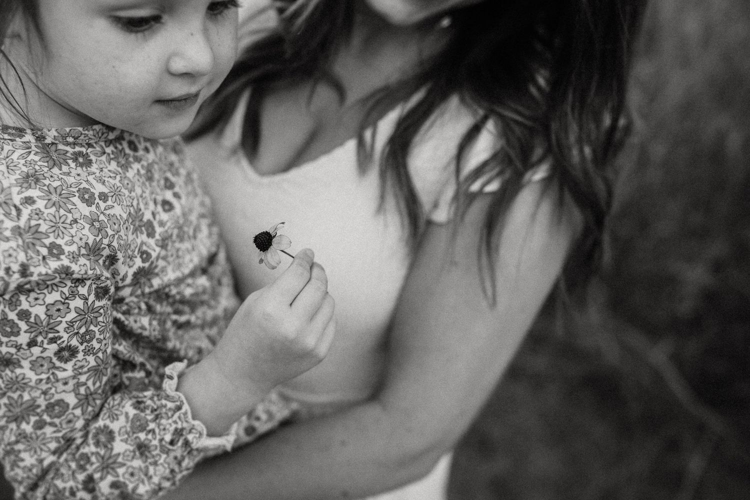 Black and white close-up of tender moment between two people with floral dress detail.