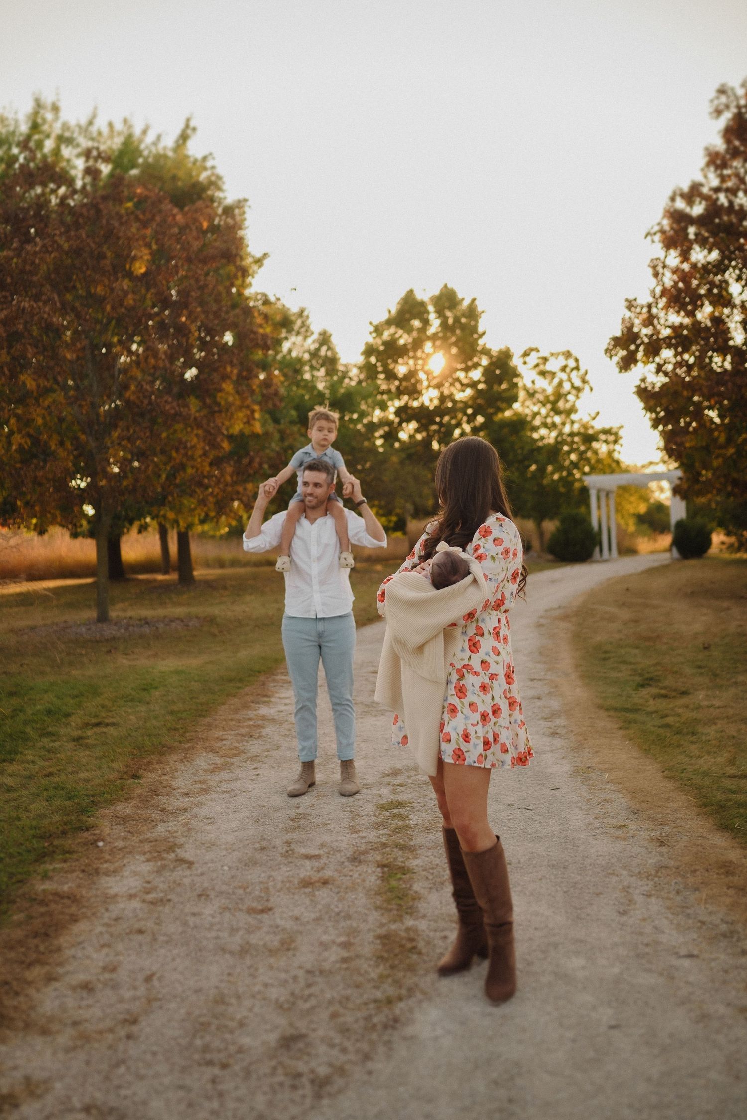 Family enjoying playful moments on dirt path during golden sunset.
