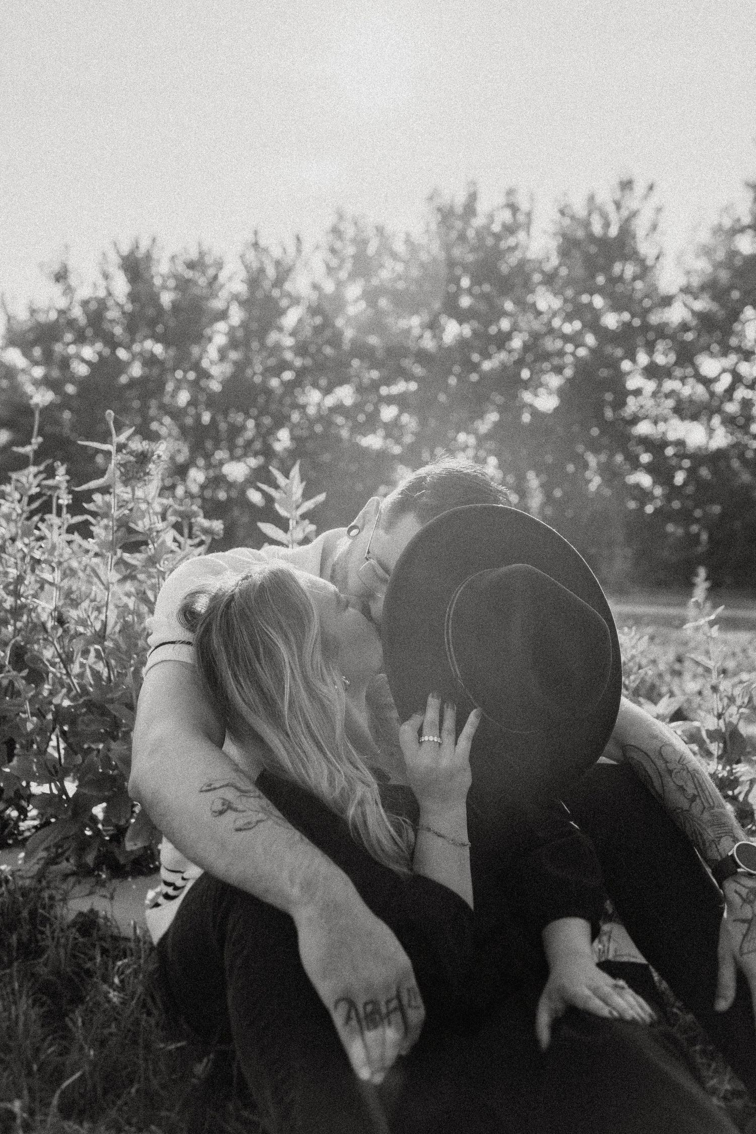 Black and white romantic photograph of a couple sharing an intimate moment in a garden.